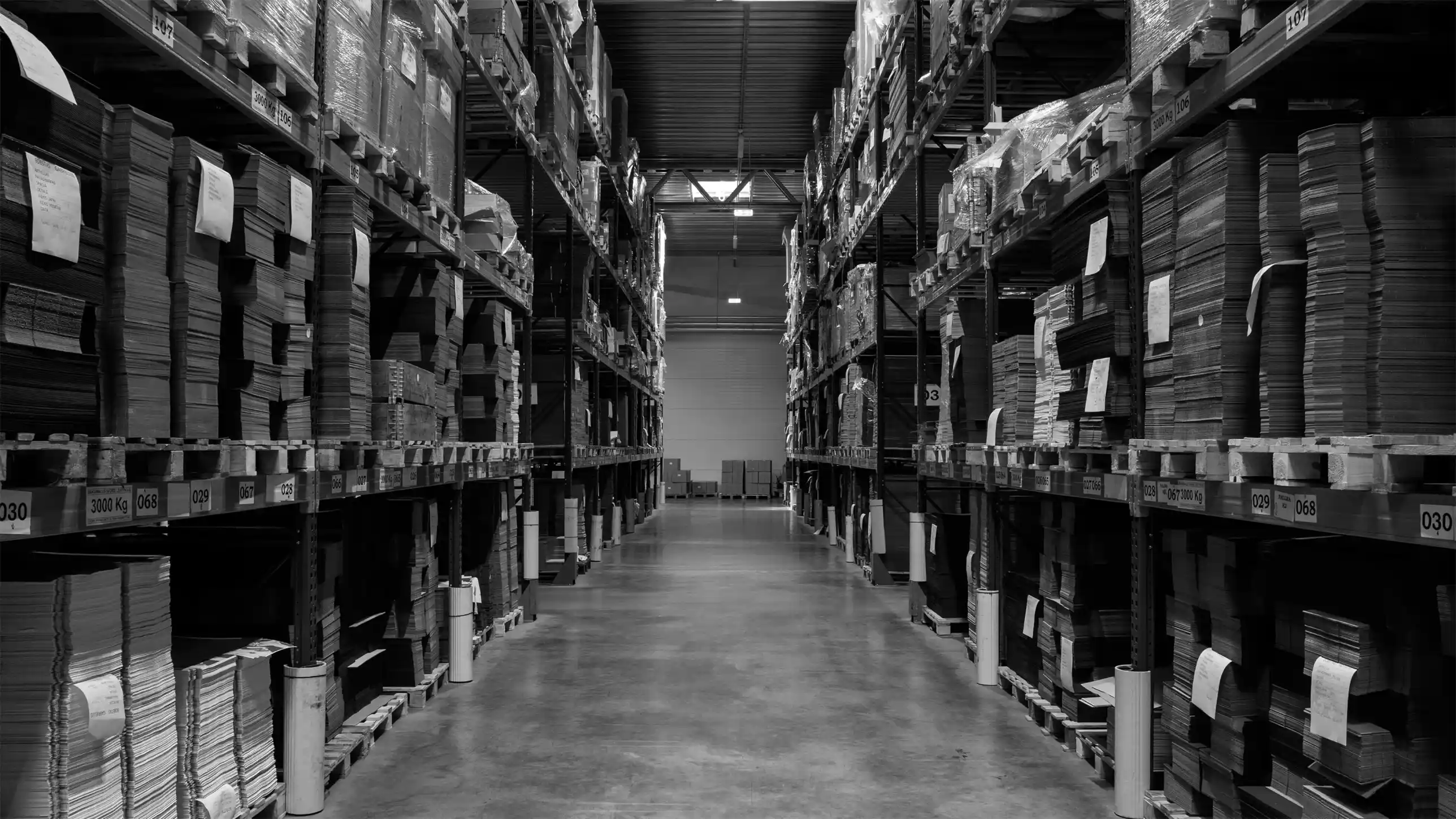 Bigso warehouse storage racks filled with stacked cardboard sheets and packaging materials, showcasing large-scale production and distribution capacity.
