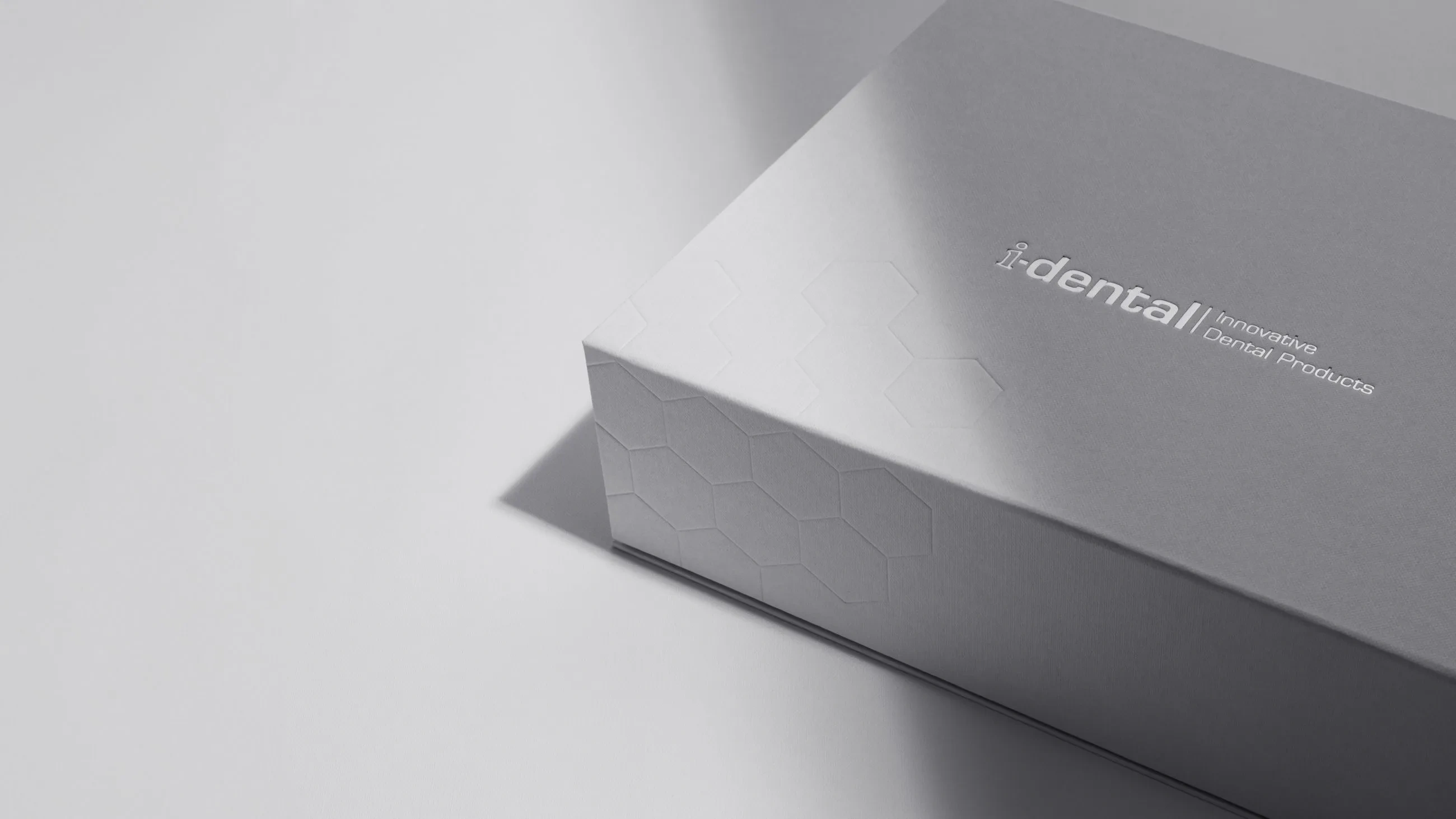 Elegant grey i-dental product packaging case manufactured by Bigso, featuring embossed hexagon pattern and silver foil logo for premium dental products.