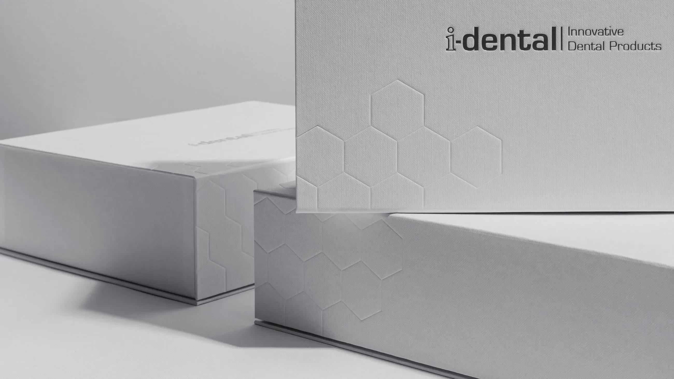 Minimalist white i-dental product packaging by Bigso with embossed hexagon design, premium cardboard case for innovative dental products.