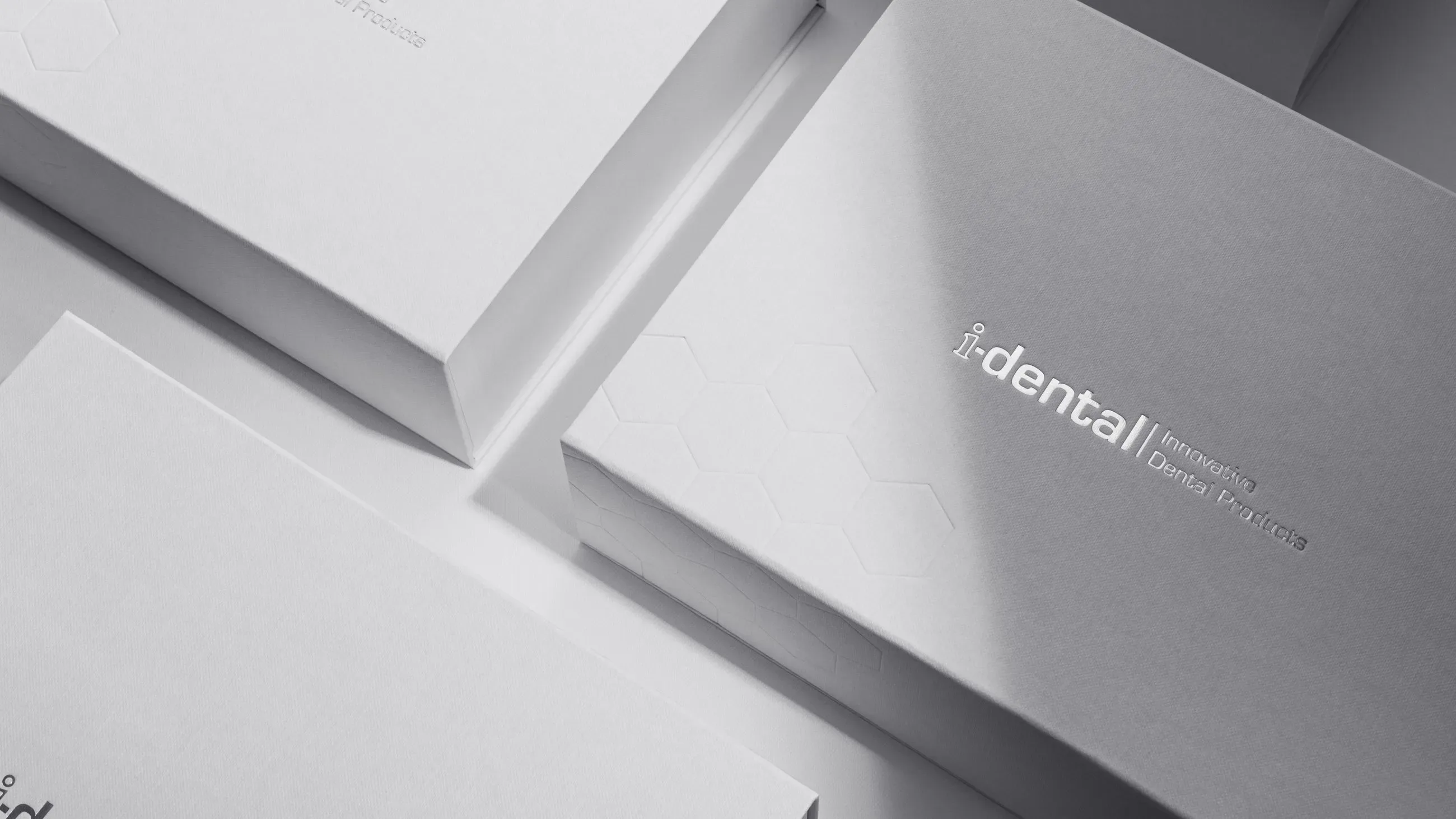 Elegant white i-dental packaging by Bigso with embossed hexagon pattern and silver foil logo, premium custom box for innovative dental products.