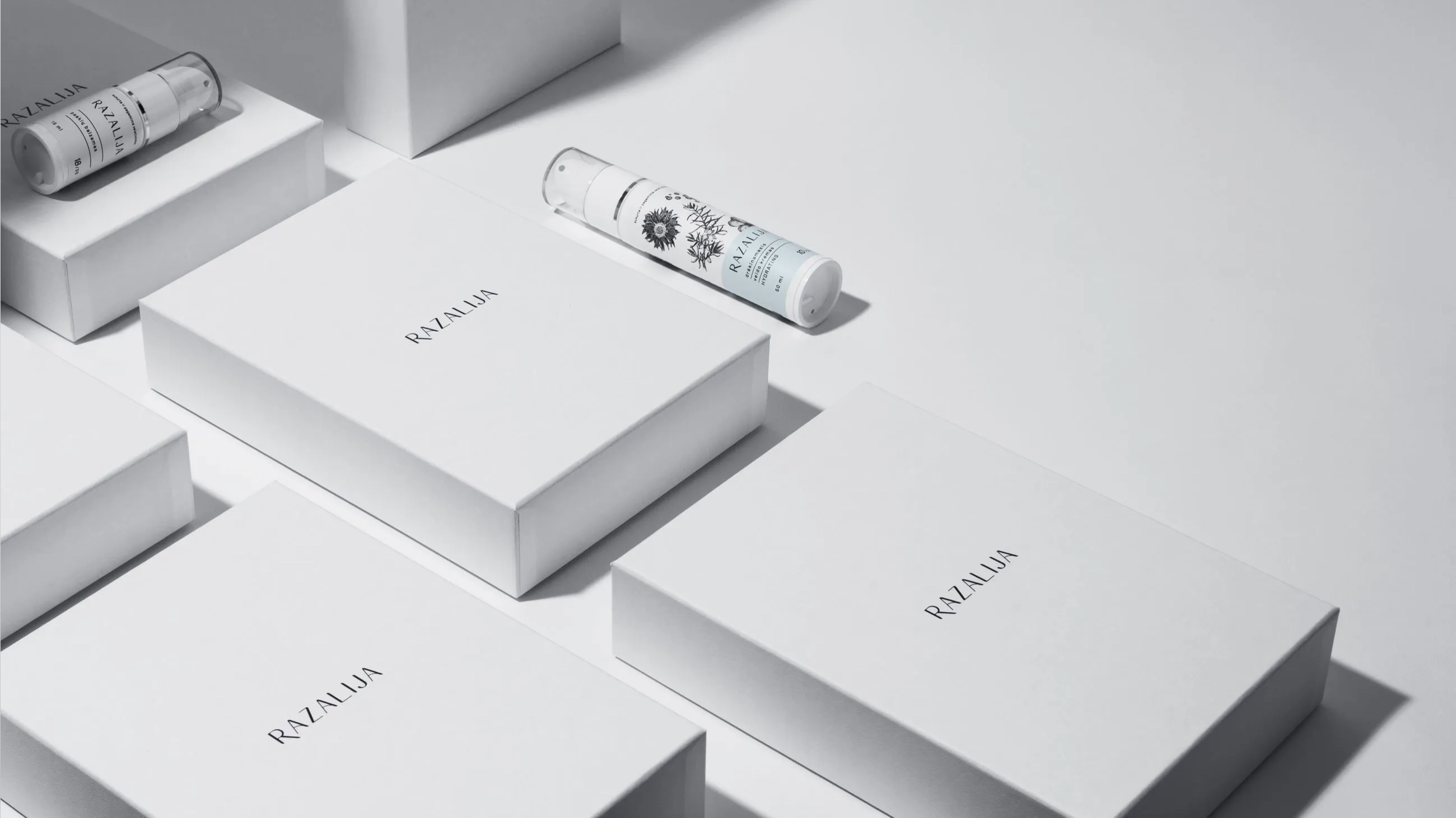 Premium minimalist packaging design for Razalija skincare, featuring white cosmetic boxes and elegant pump bottles with botanical illustrations, created by Bigso.