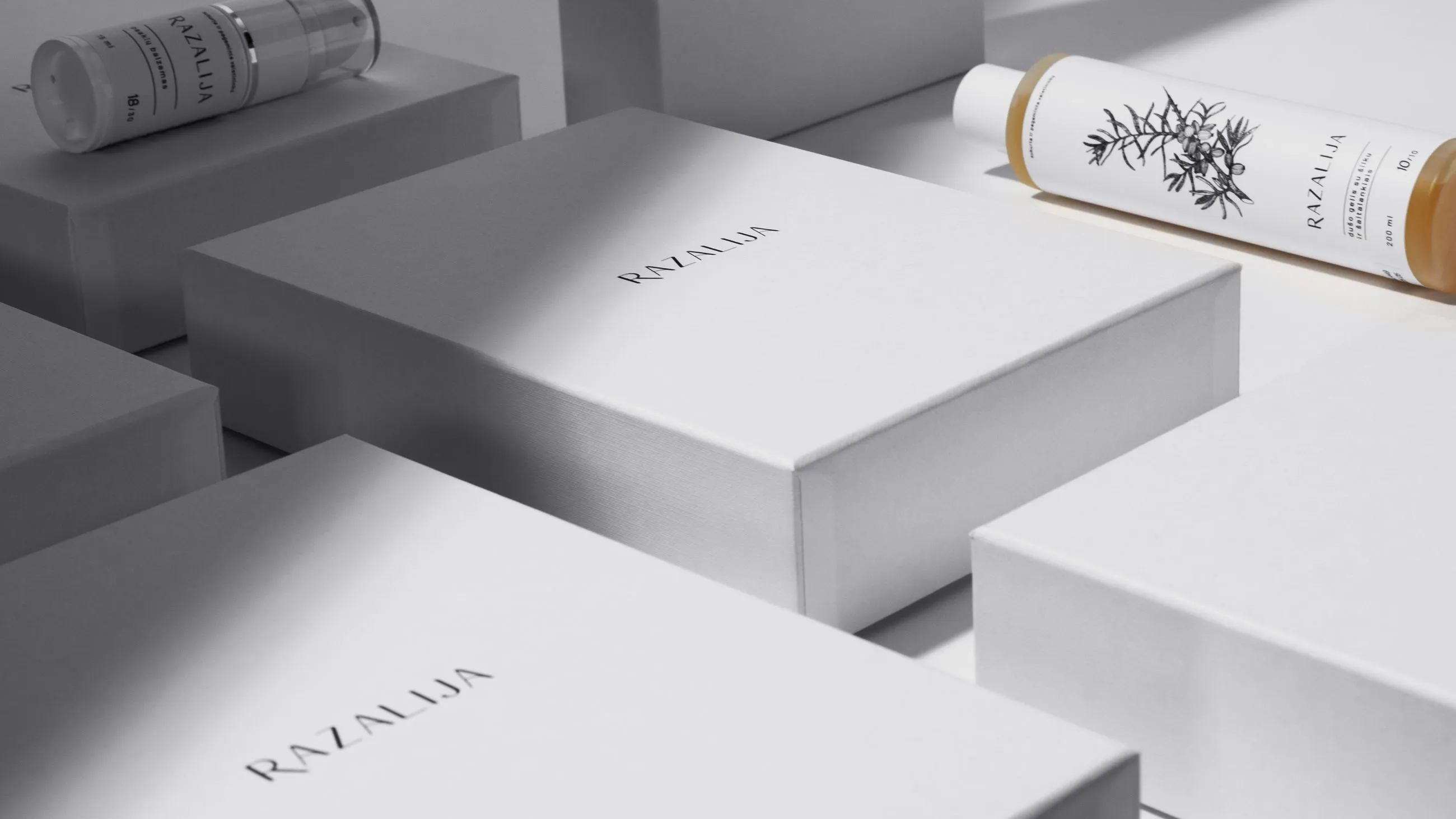 Elegant Razalija skincare packaging with minimalist white boxes and premium cosmetic bottles featuring botanical illustrations, captured in soft lighting for a luxurious brand aesthetic.