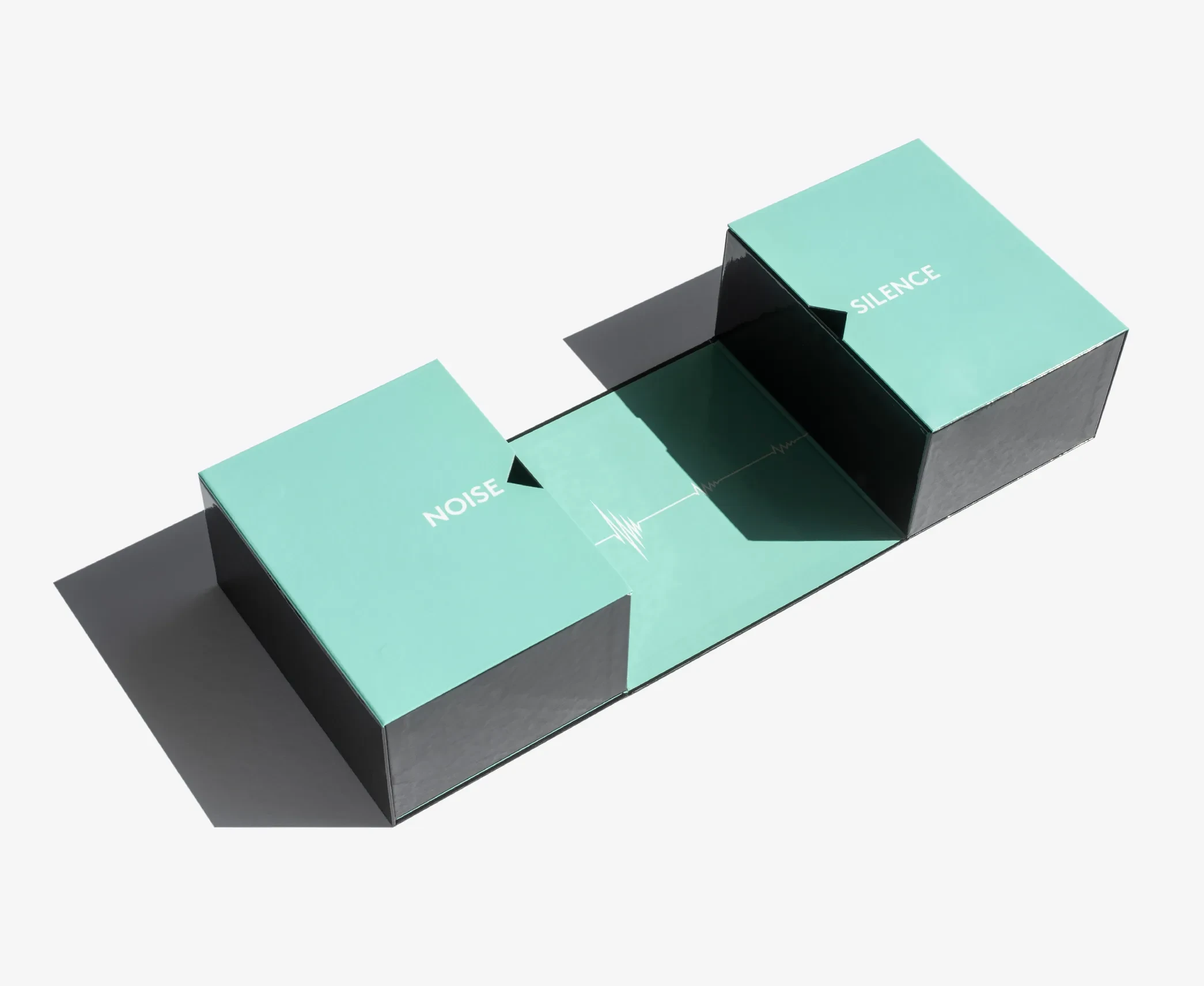A dual-section transformer rigid box in turquoise and black, opened to reveal “Noise” and “Silence” compartments.