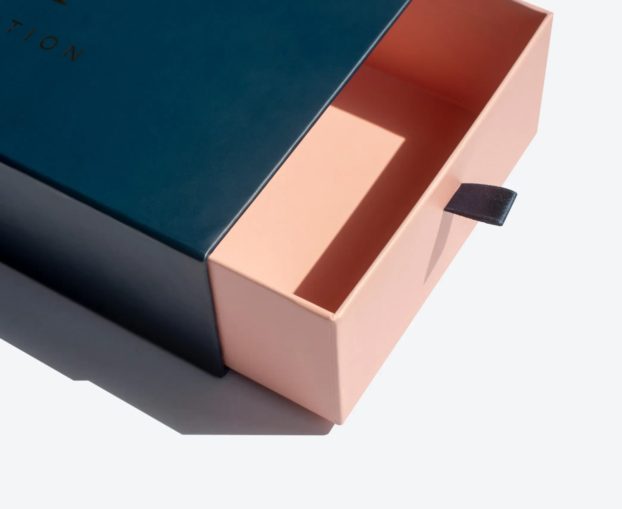 Close-up of the blush pink tray of a navy blue drawer box, highlighting the pull-tab and smooth finish.