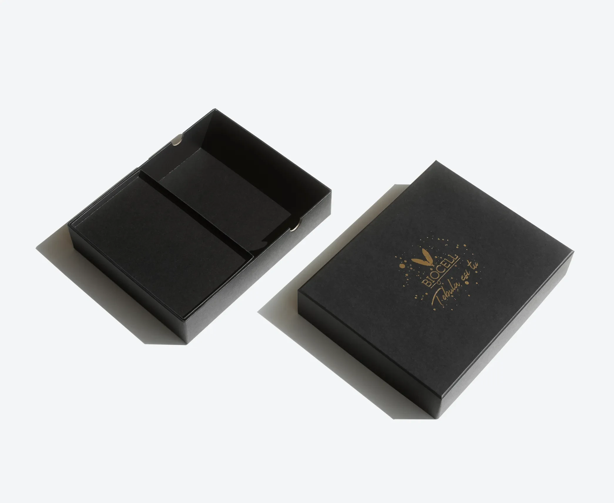 Black rigid lid and base box with gold foil logo, displayed with lid removed to show two inner compartments.