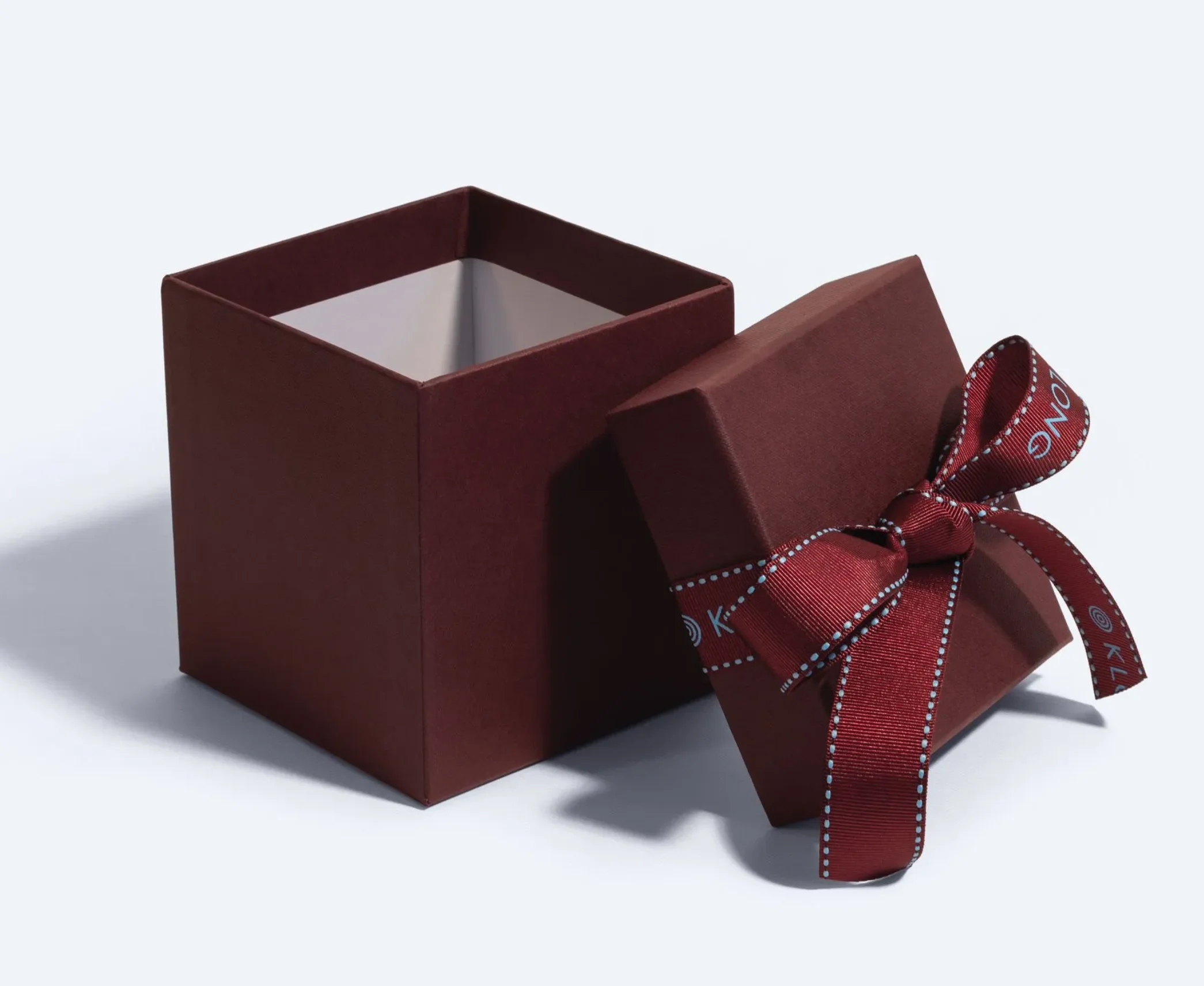 Burgundy rigid lid and base box with matching ribbon tied in a bow, used for premium gift packaging.