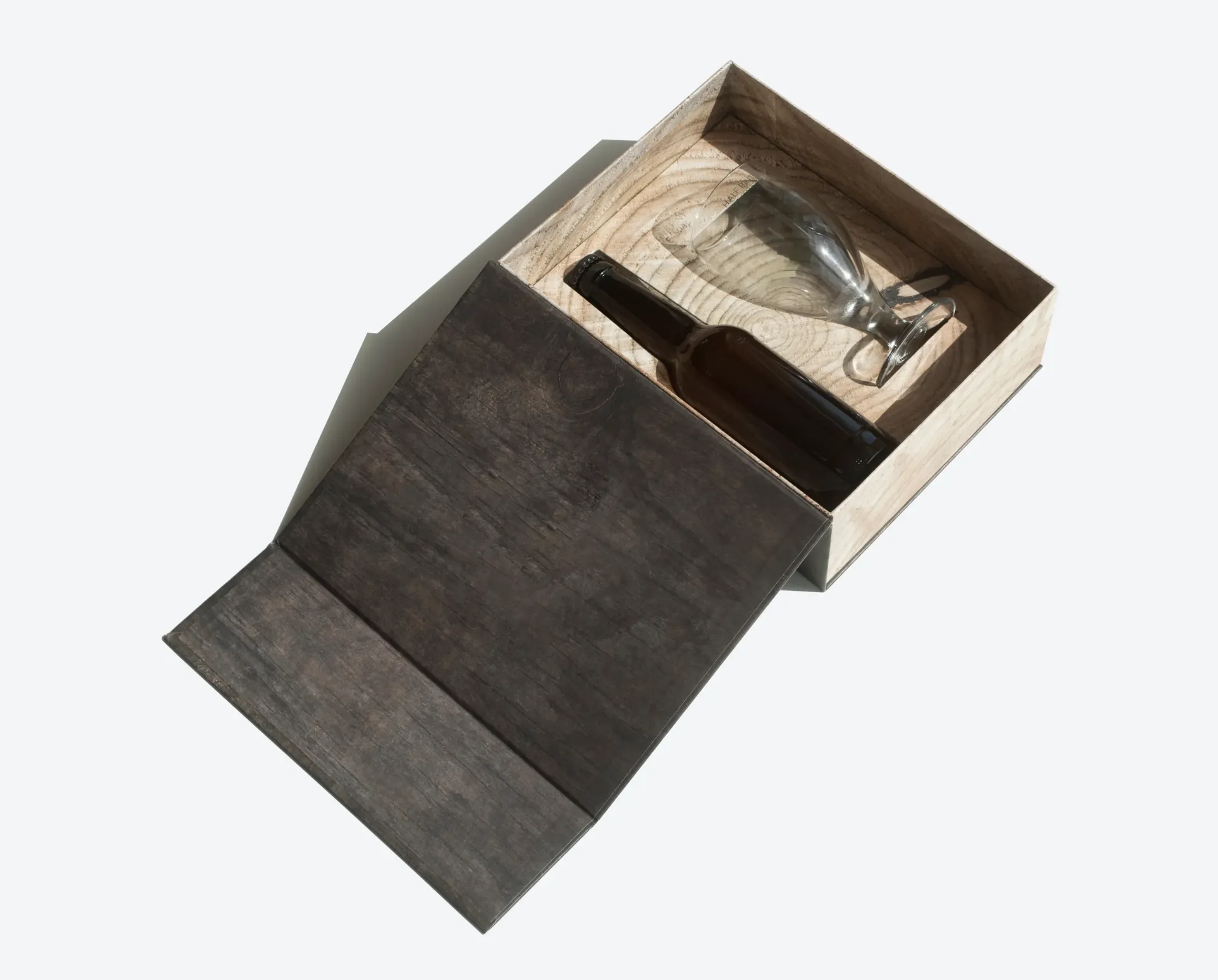 A rustic-style magnetic box with a wooden finish, open to display a wine bottle and a glass inside.
