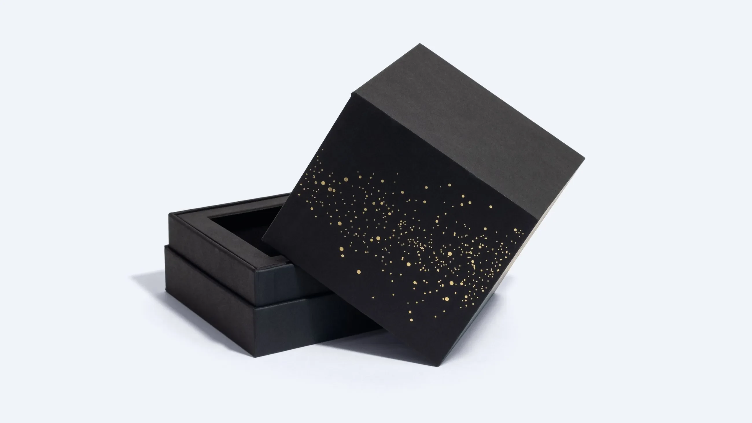 Black neck box with golden speckled design – A luxury black rigid neck box with a shoulder structure, decorated with scattered gold foil dots on the lid, shown partially open.