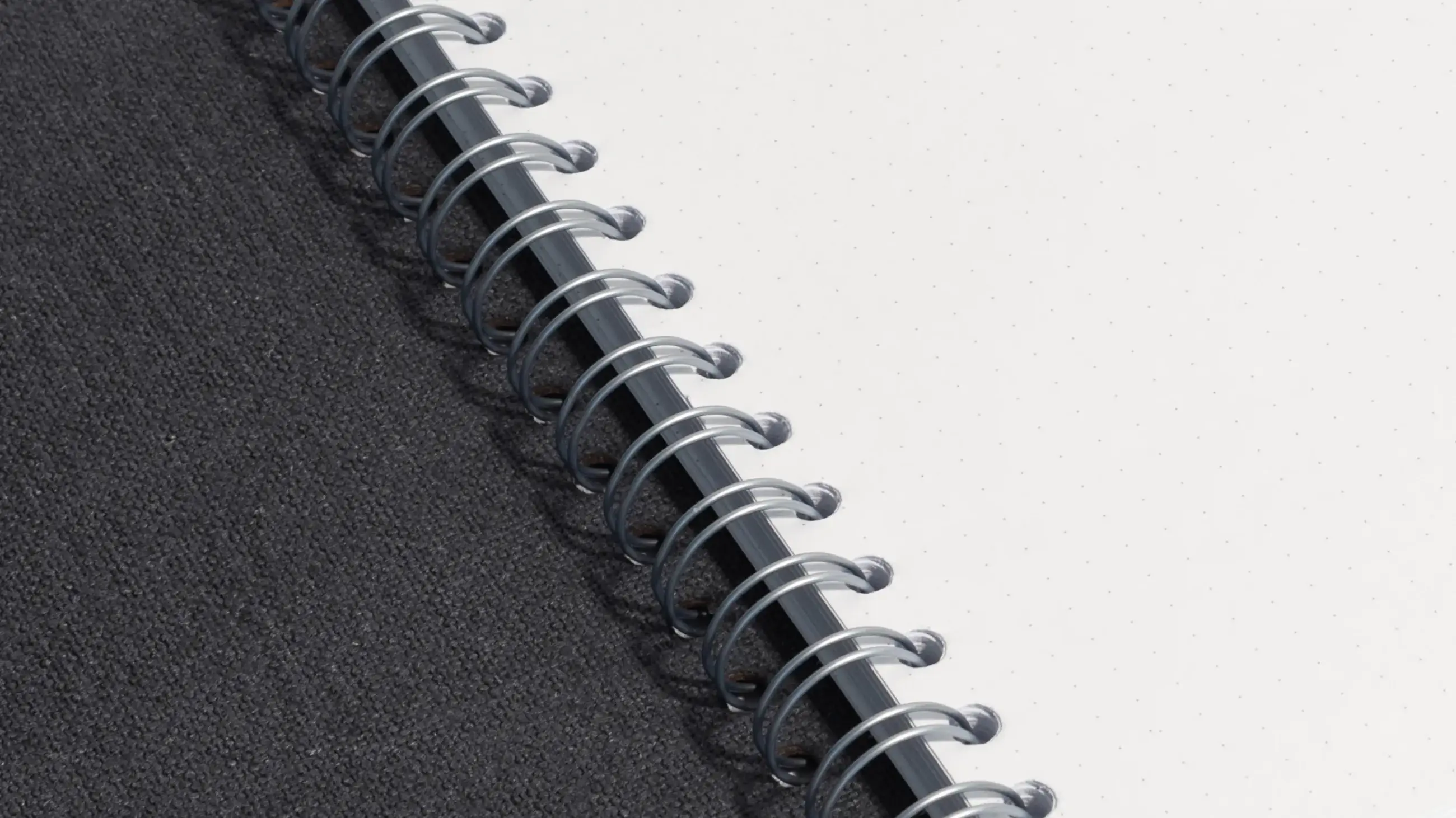Close-up of spiral binding on a black notebook showing detailed stitching and dotted pages.