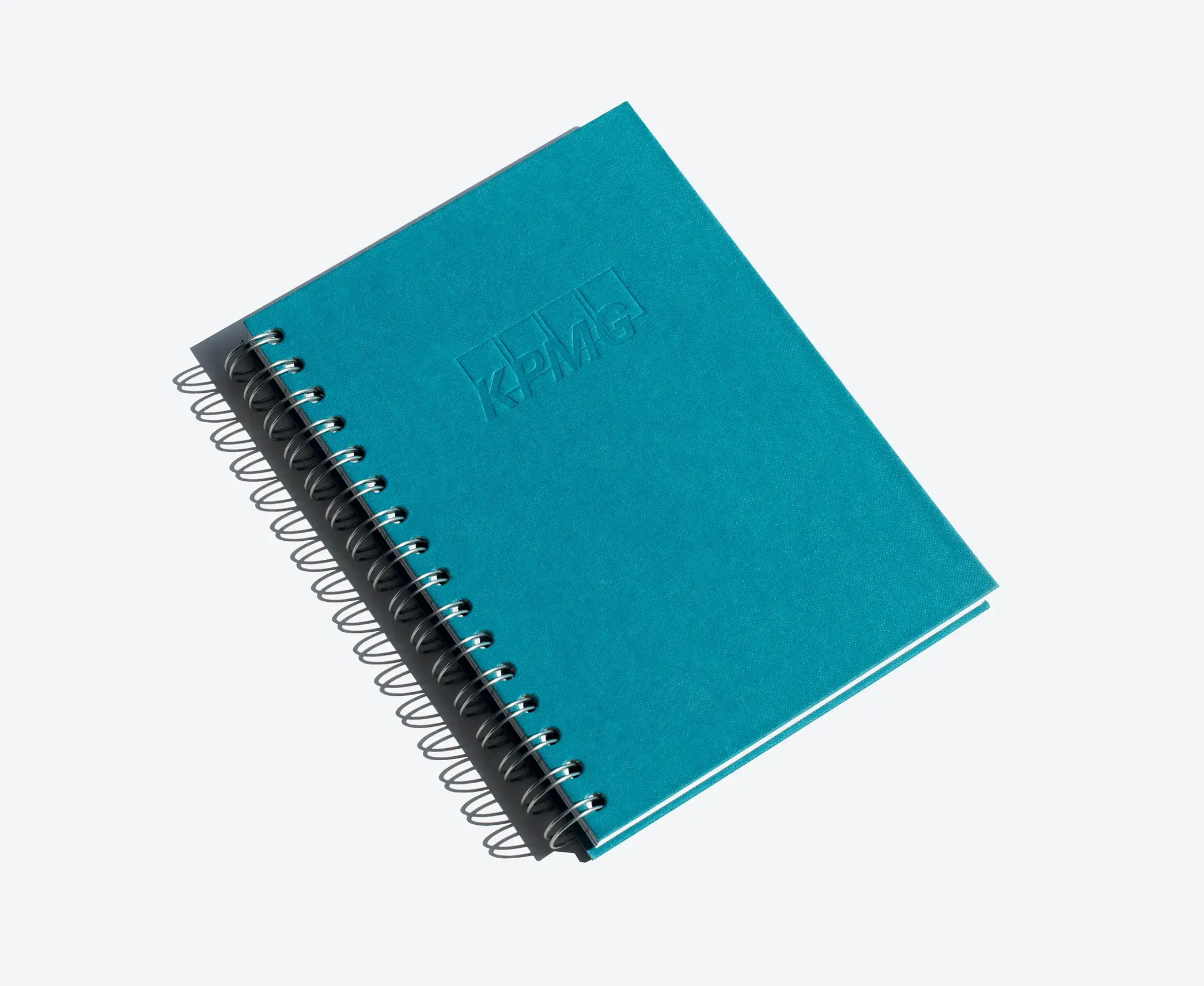 Blue rigid notebook with KPMG logo embossed on the cover and silver spiral binding.