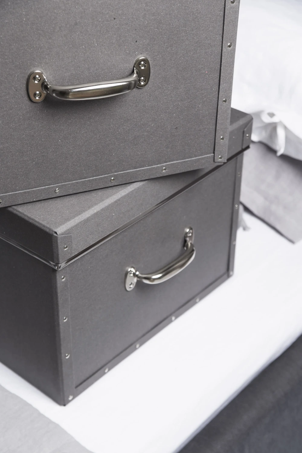 Stack of sturdy grey storage boxes from Bigso, made of durable recycled fiberboard with riveted edges and sleek chrome handles. These eco-friendly organizing boxes combine industrial strength with Scandinavian design, offering sustainable storage solutions for home and office.