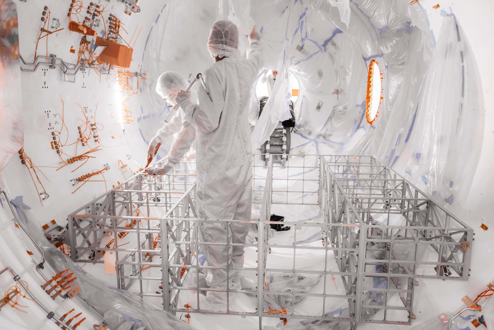 A cleanroom-suited Vast employee joins metal tubes under a gasket on Haven-1's hull.