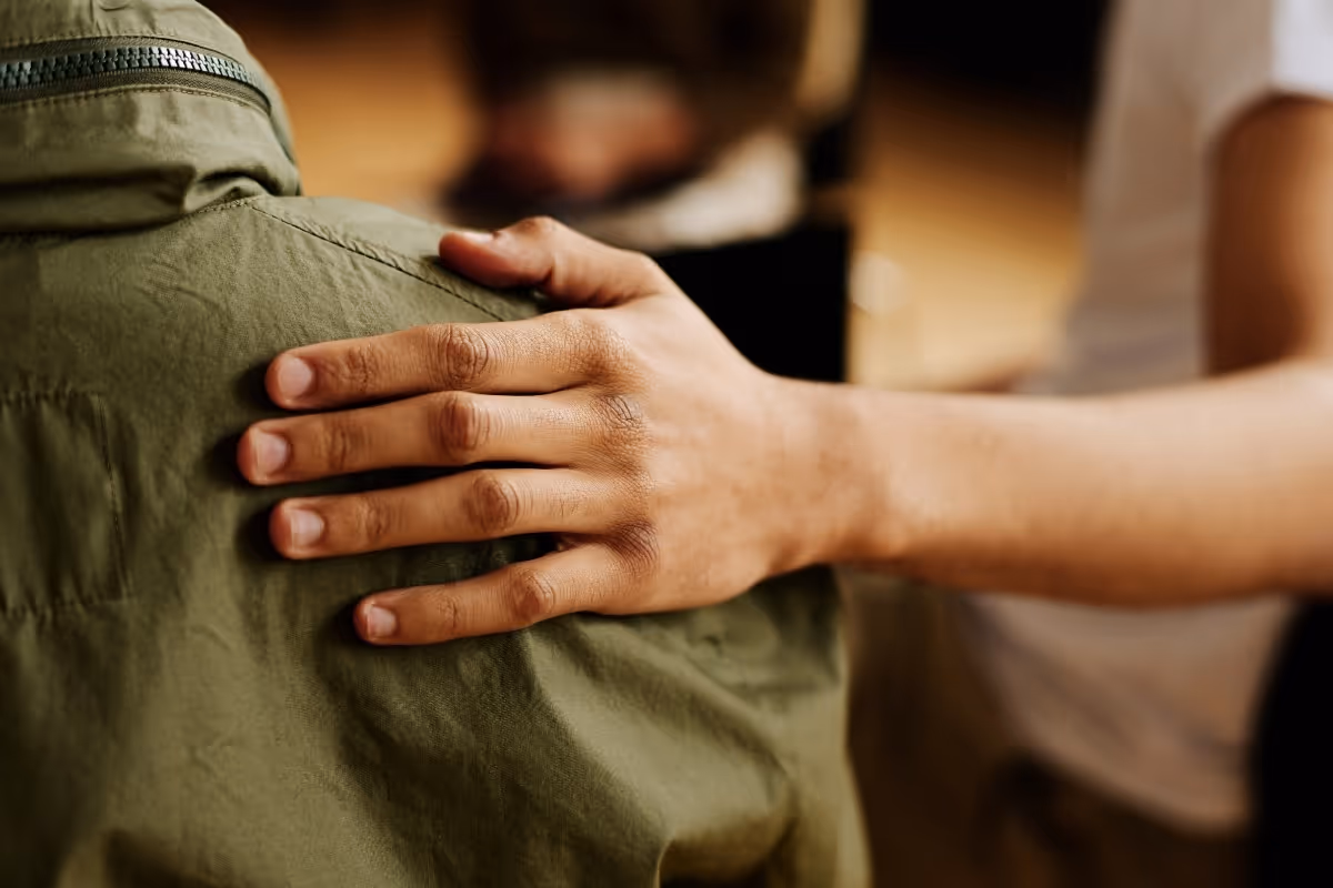 a male hand on the shoulder of another individual