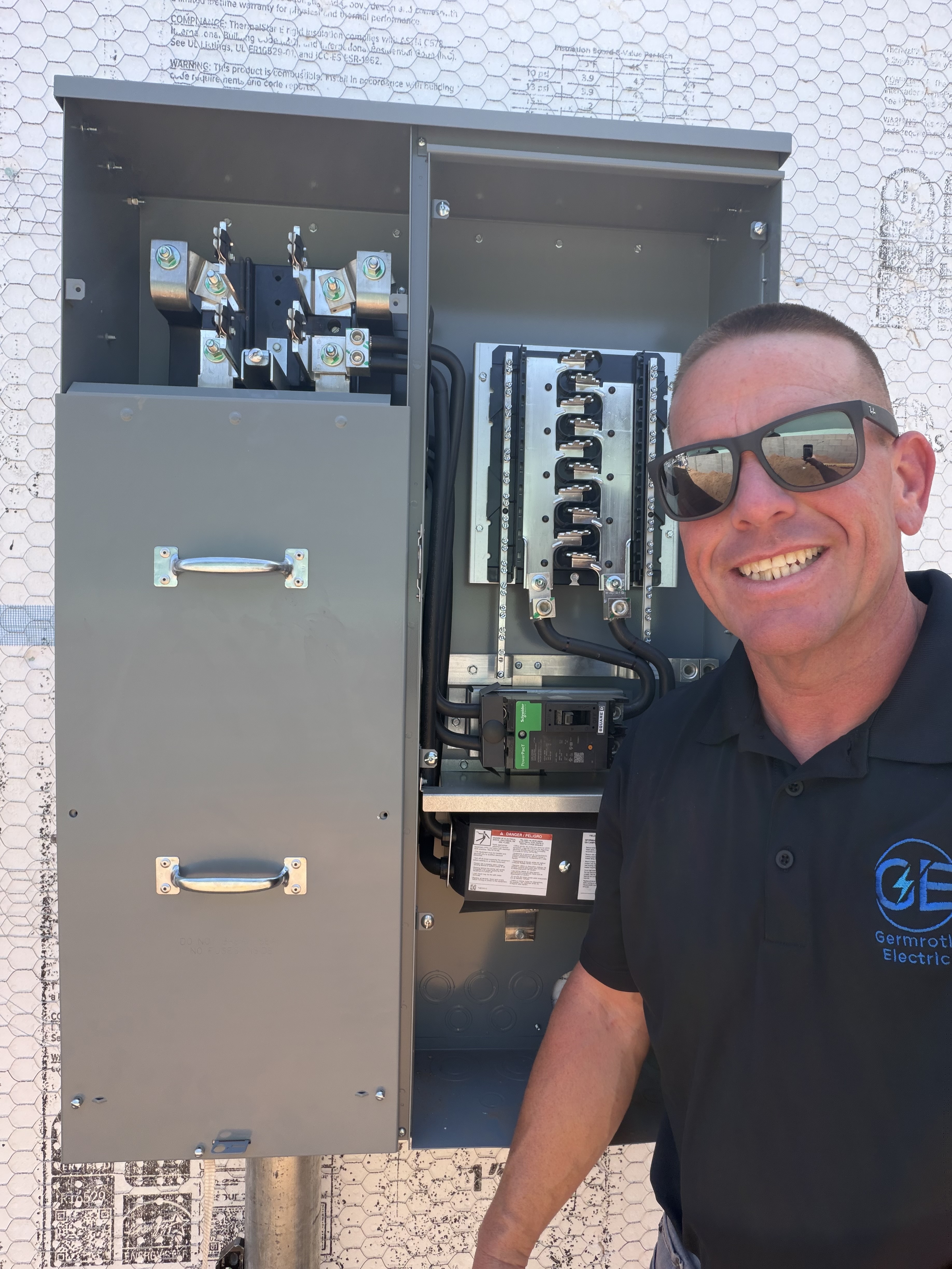 Adam Germroth standing next to a complete & open electrical panel