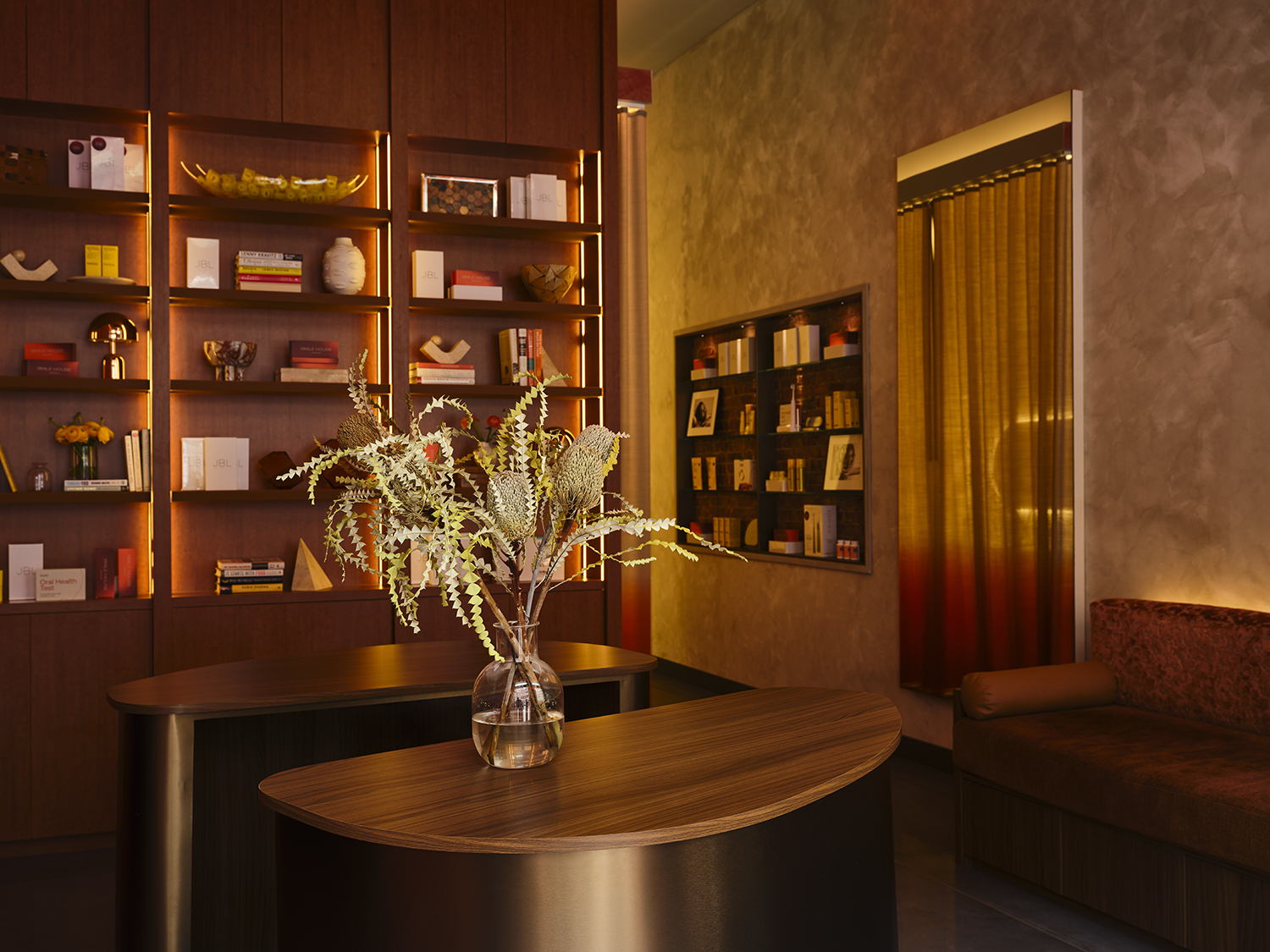 Smile House reception lounge with backlit walnut library shelving and warm plaster walls