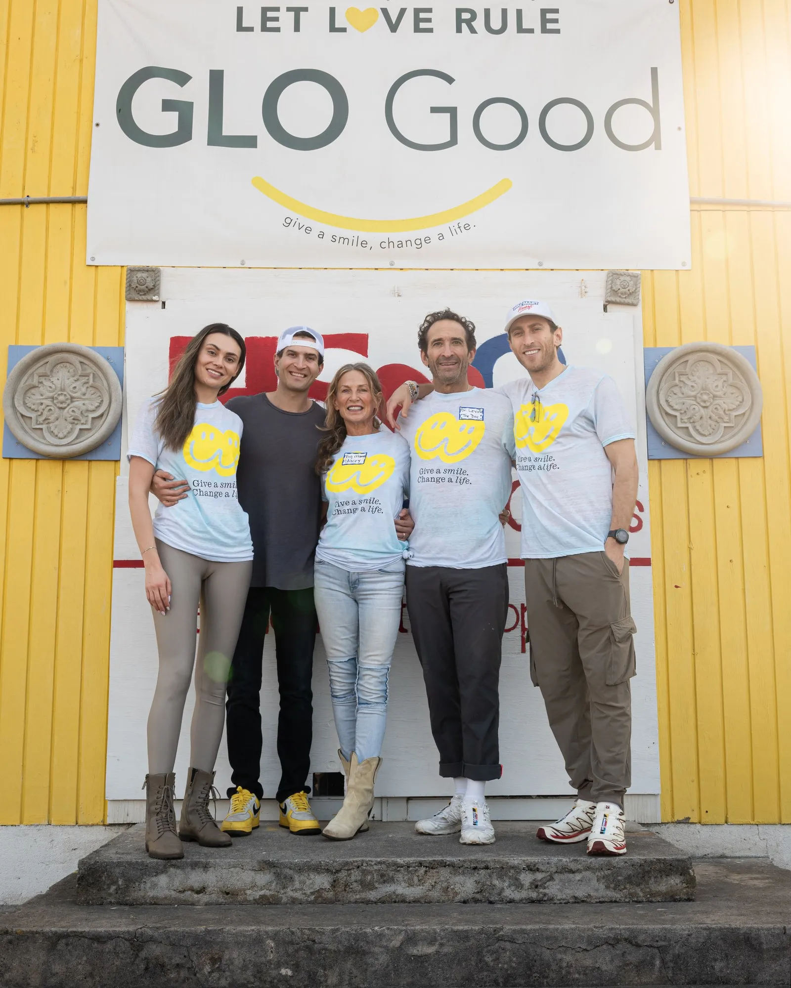 The Levine family in GLO Good shirts beneath the GLO Good sign at a mission
