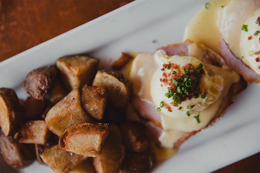 Plated eggs benedict and home fries.