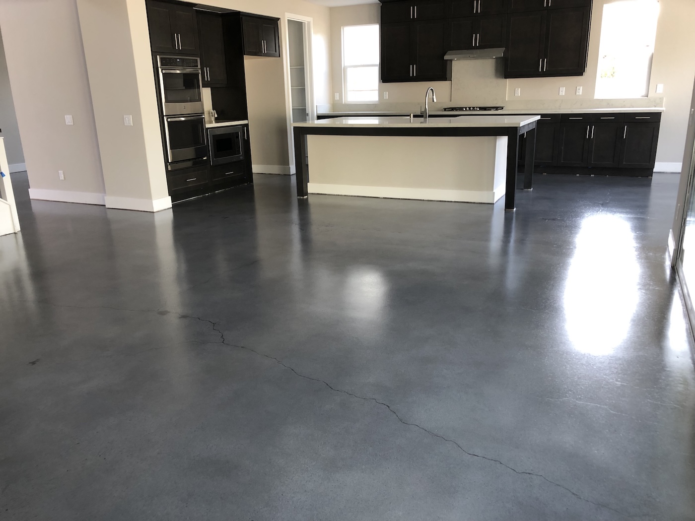 Modern residential living space featuring a deep, dark gray polished concrete floor with a seamless architectural finish.