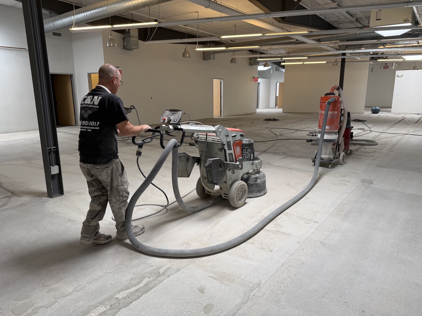 Professional concrete surface preparation featuring a contractor operating a high-performance Husqvarna planetary grinder to create a smooth, clean floor finish.
