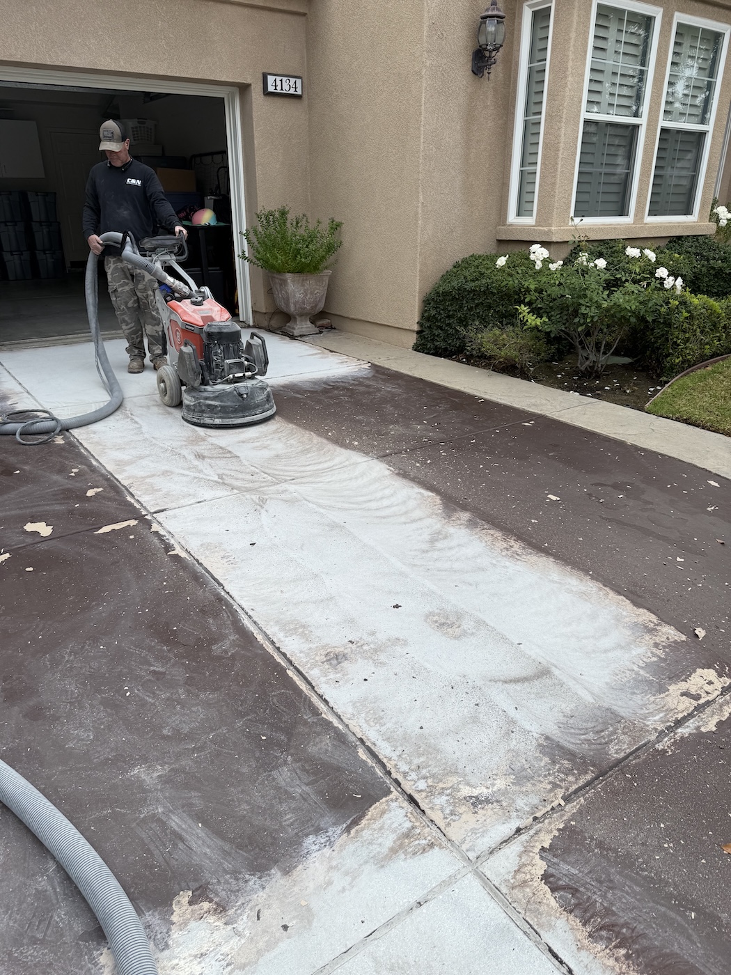 C&N technician operating a heavy planetary diamond grinder with HEPA dust extraction to strip an old coating off a residential concrete driveway in Ventura County.