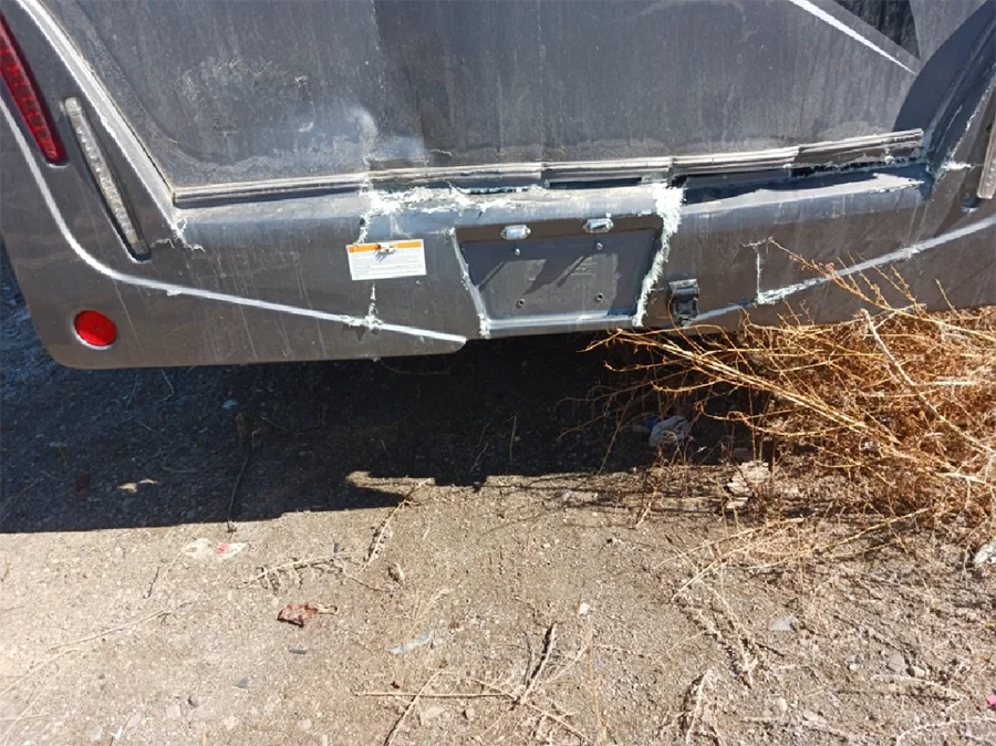 Daños en la parte trasera de un remolque de autocaravana después de una colisión con un camión, que muestran paneles exteriores agrietados y daños por impacto causados por un choque trasero.