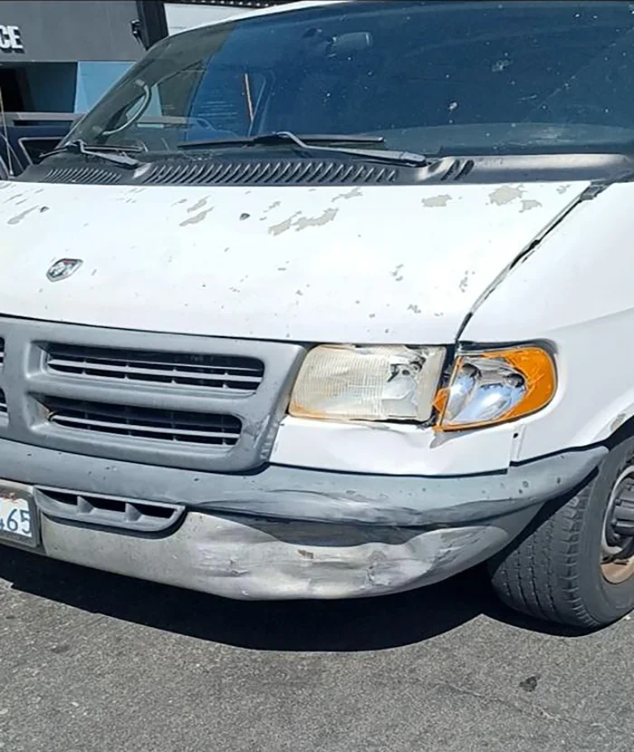 Daños en la parte delantera de una camioneta blanca después de un accidente automovilístico en Los Ángeles, que muestran daños en el parachoques, los faros y la parrilla causados por una colisión en una intersección.
