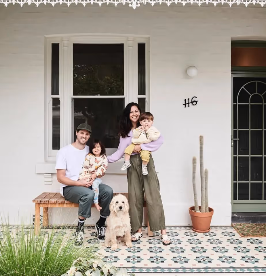 Family with two young children and a dog sitting on their front porch