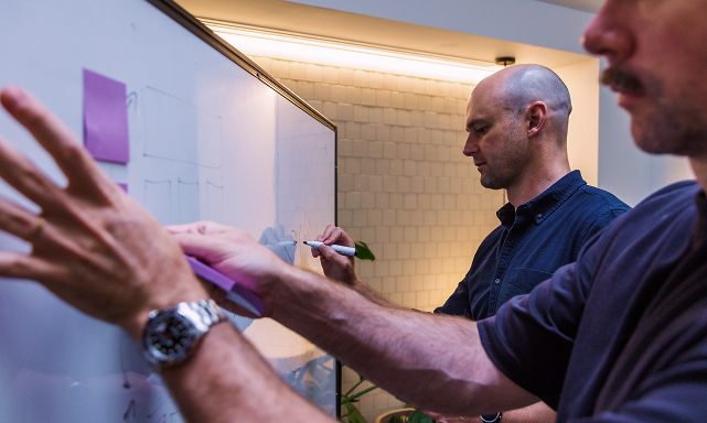 UX agency team running a collaborative design workshop with wireframes and user journey maps