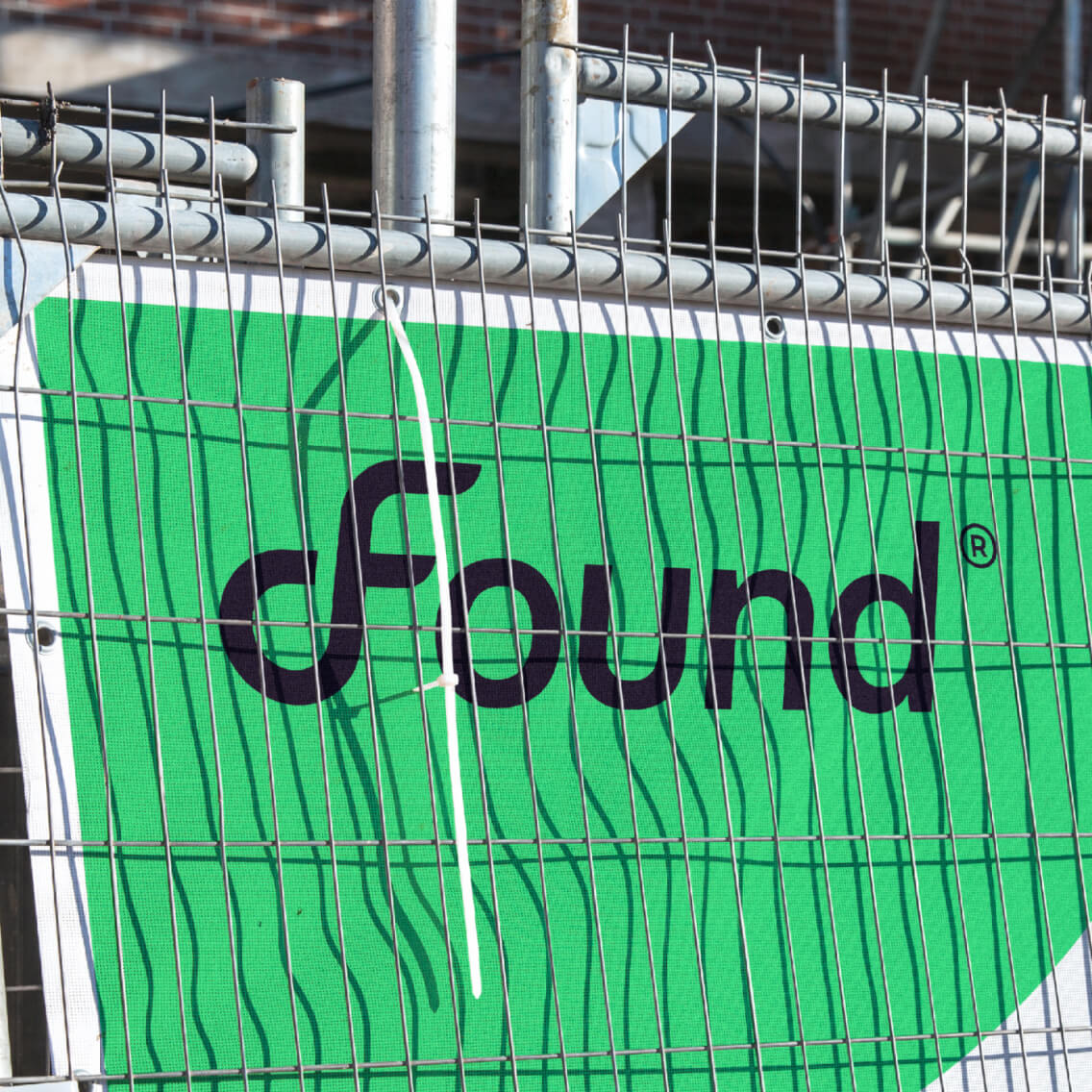 Found branded site fencing showing the electric-green palette applied across construction hoardings
