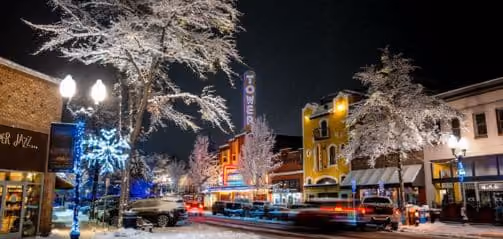 A city street is covered in snow at night.