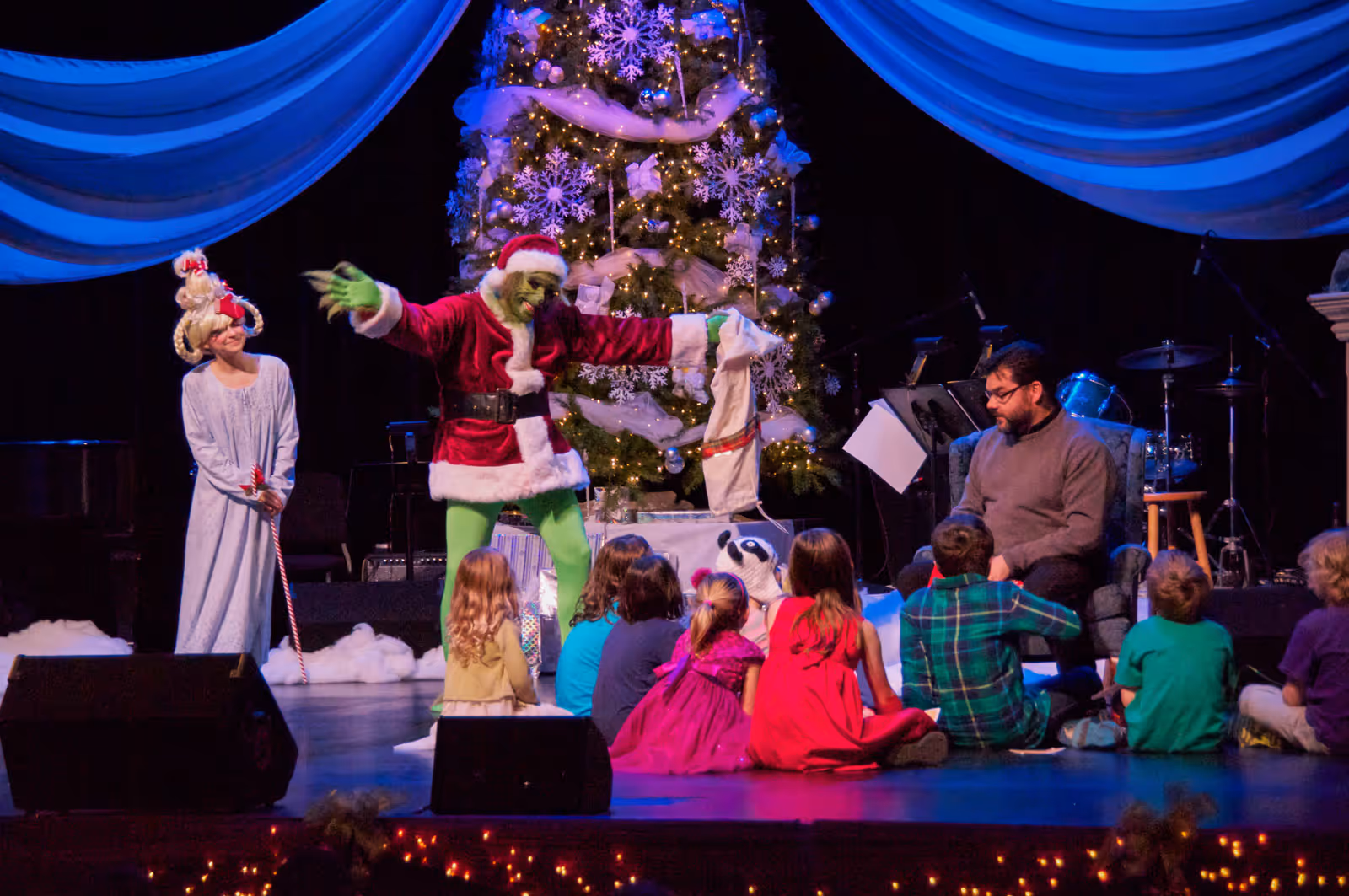 A group of people sitting around a christmas tree.