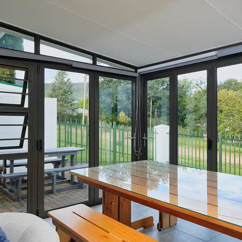 modern conservatory with wooden table and black window frames