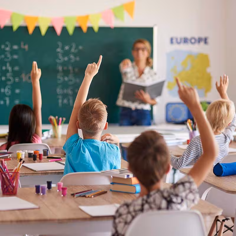 children holding hands up in classroom