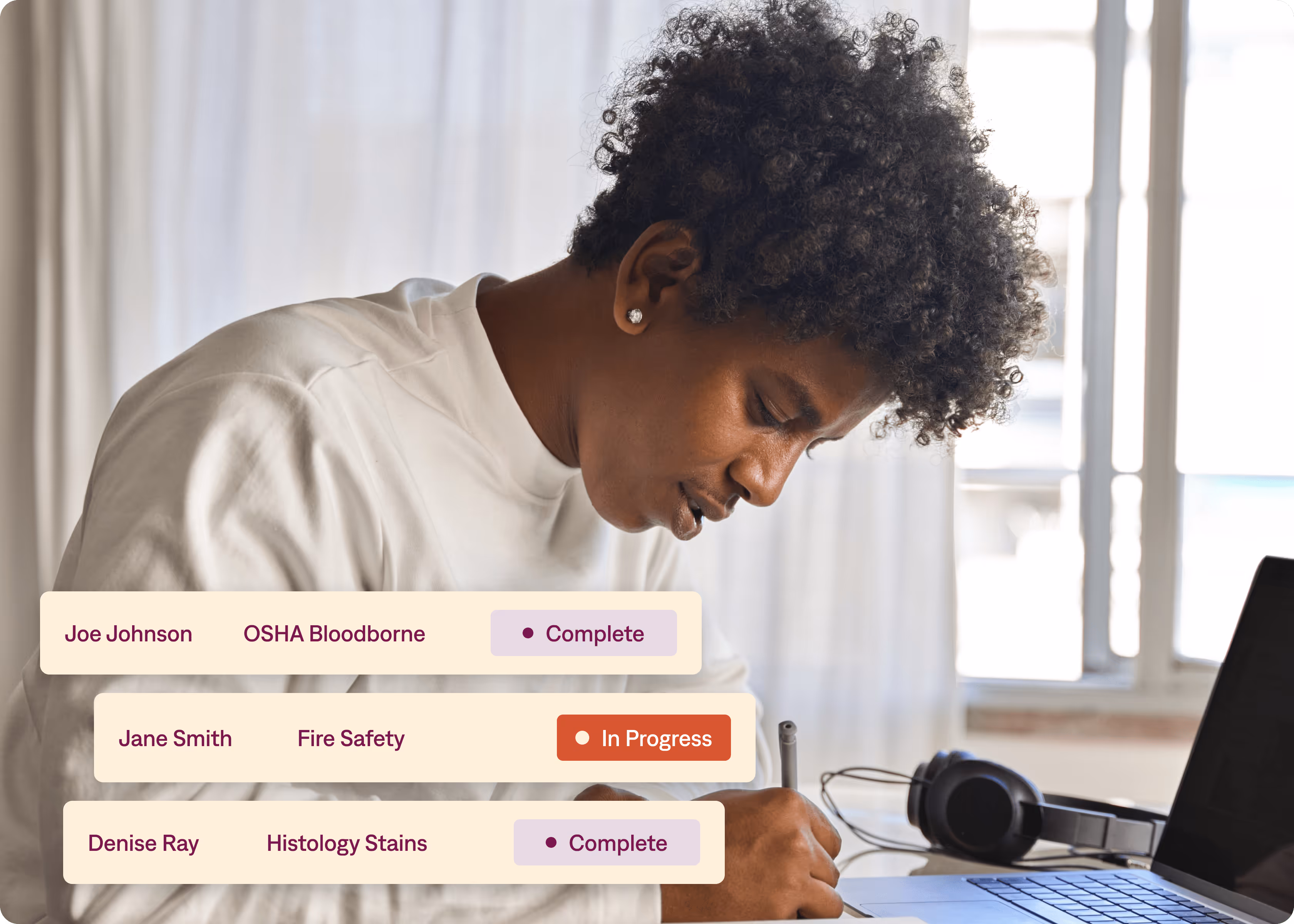 A woman is writing on a piece of paper with a laptop in the background