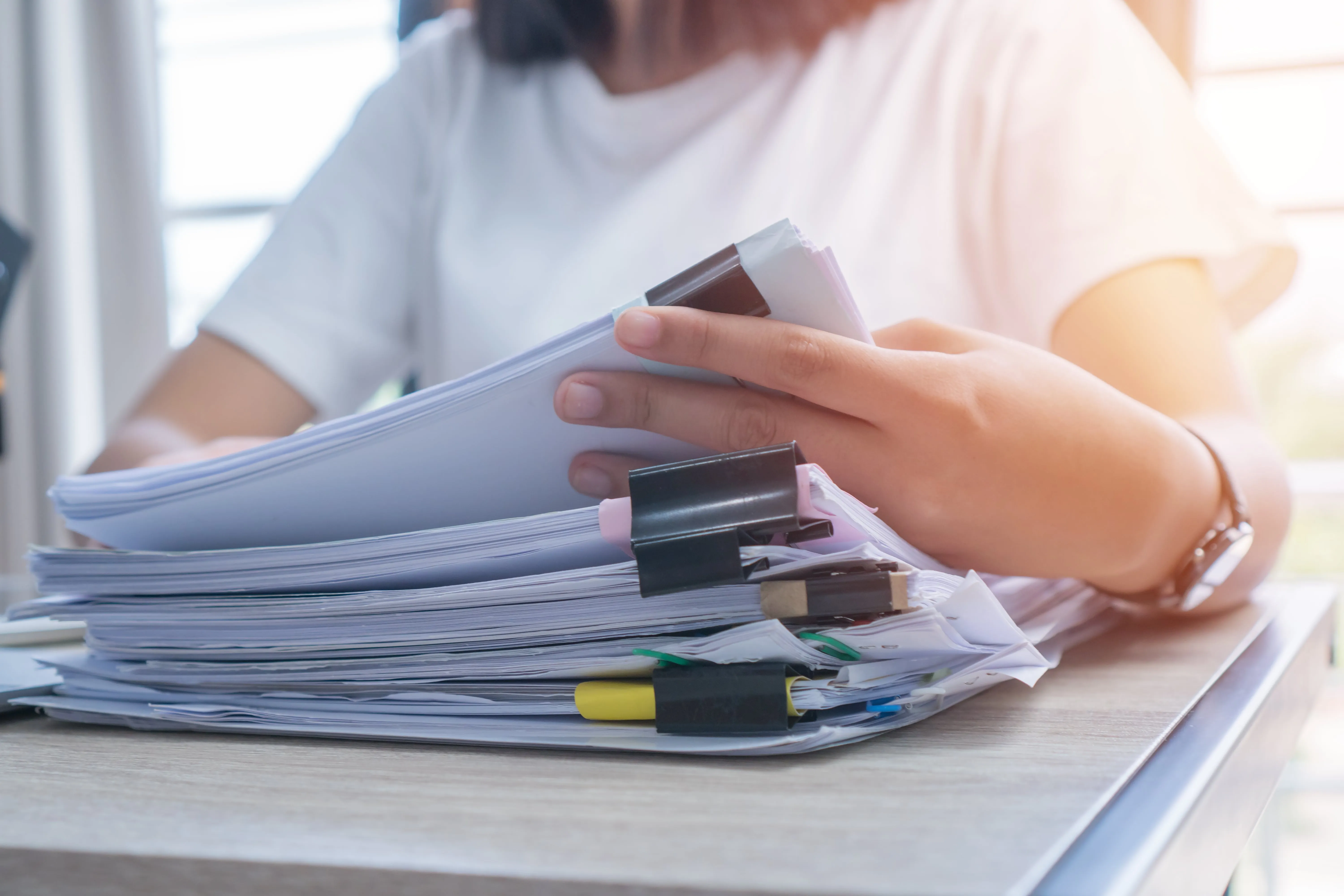 A woman is holding a stack of papers in her hand
