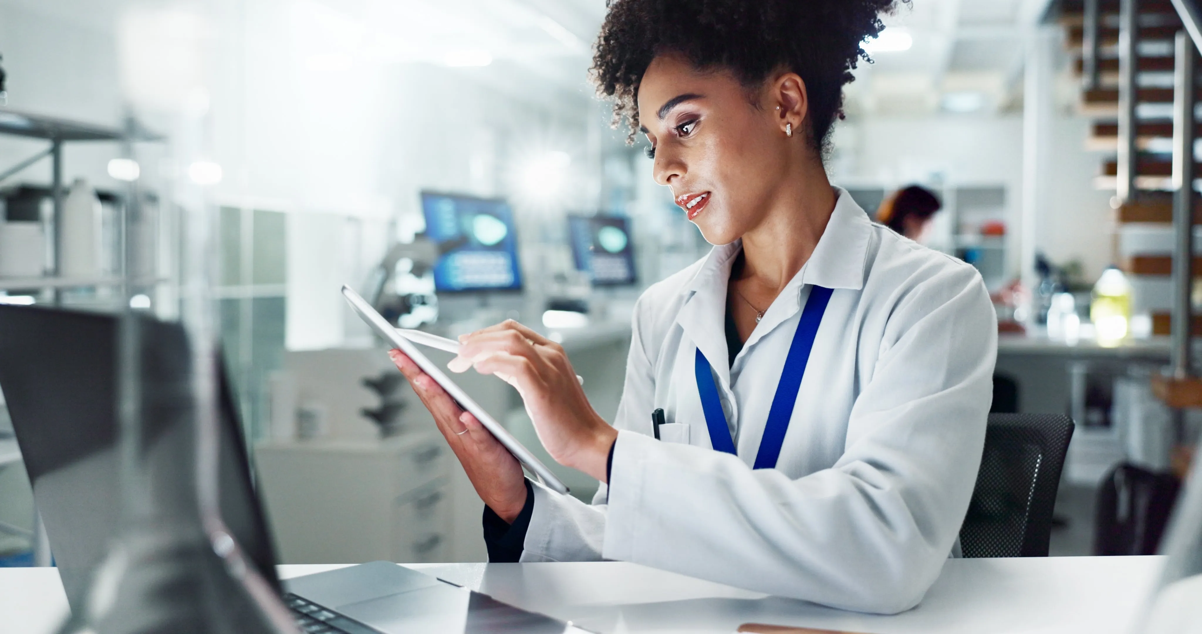 A woman in a lab coat is using a tablet