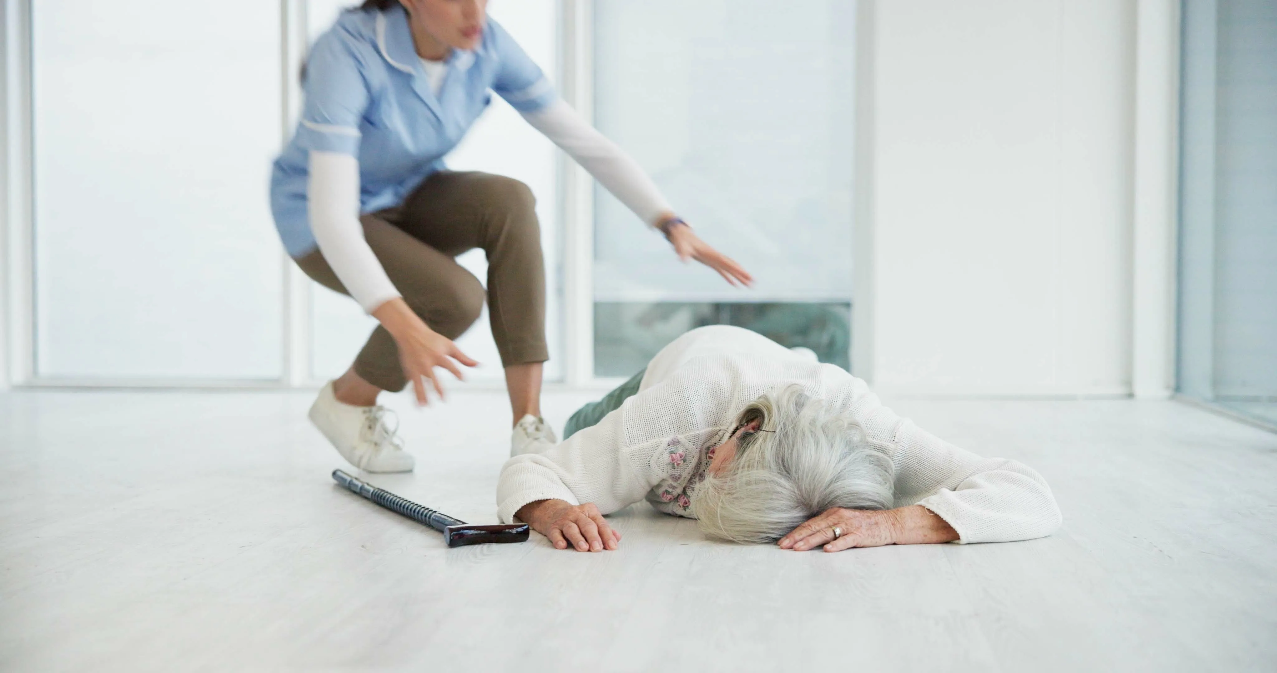 An elderly woman laying on the floor with a nurse attending her