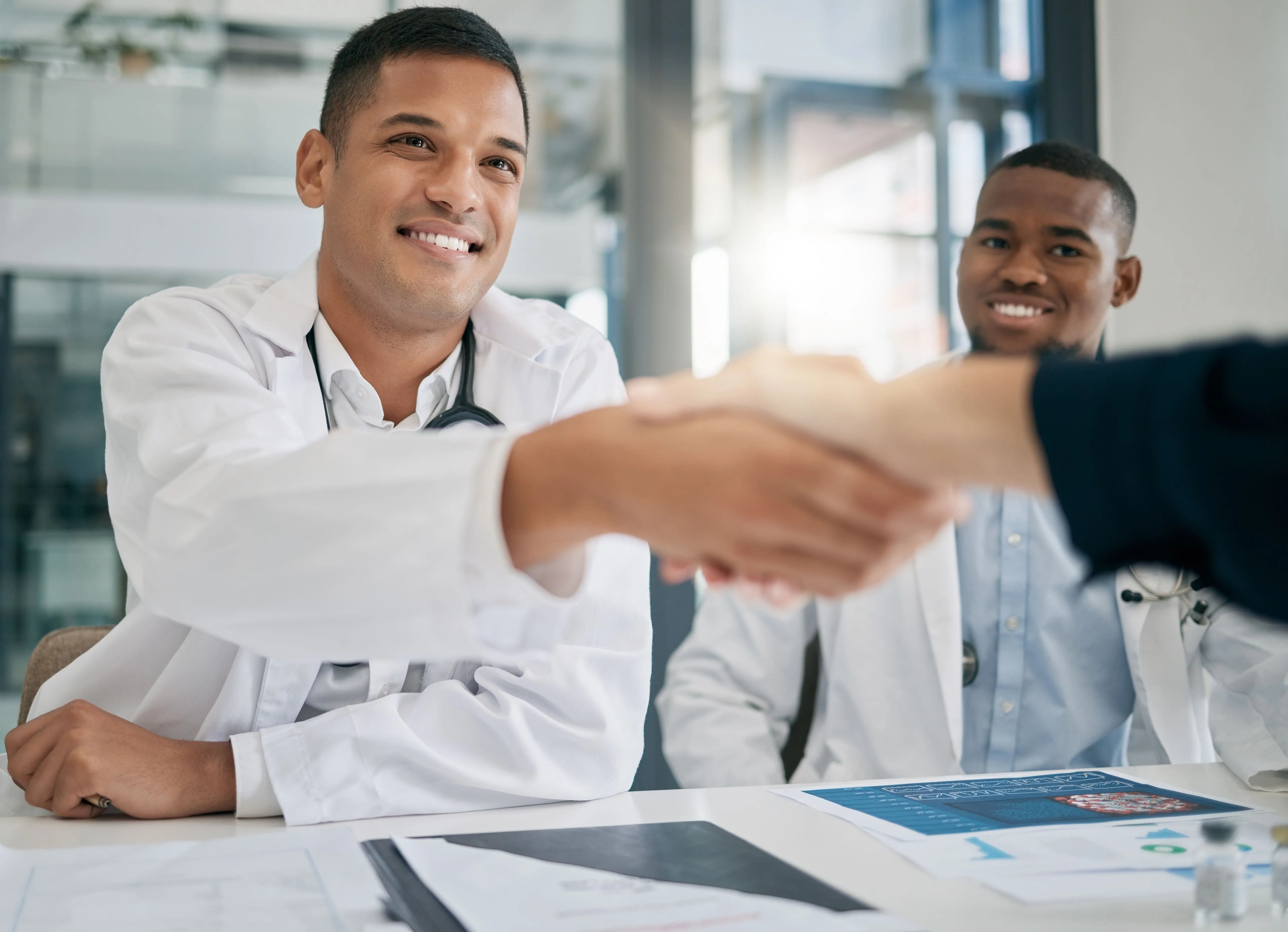 A group of doctors are shaking hands at a table