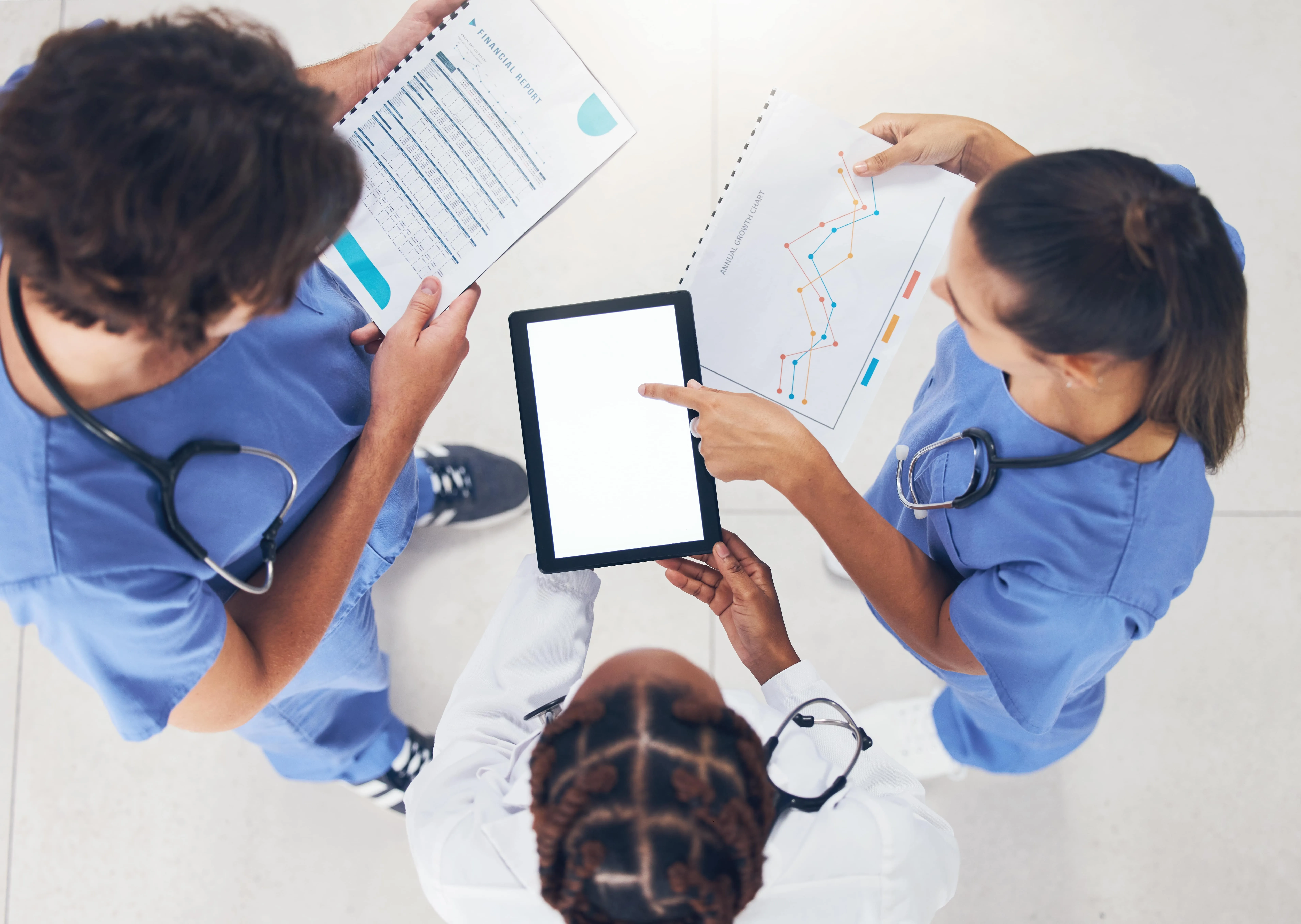 A group of doctors and nurses are looking at a tablet