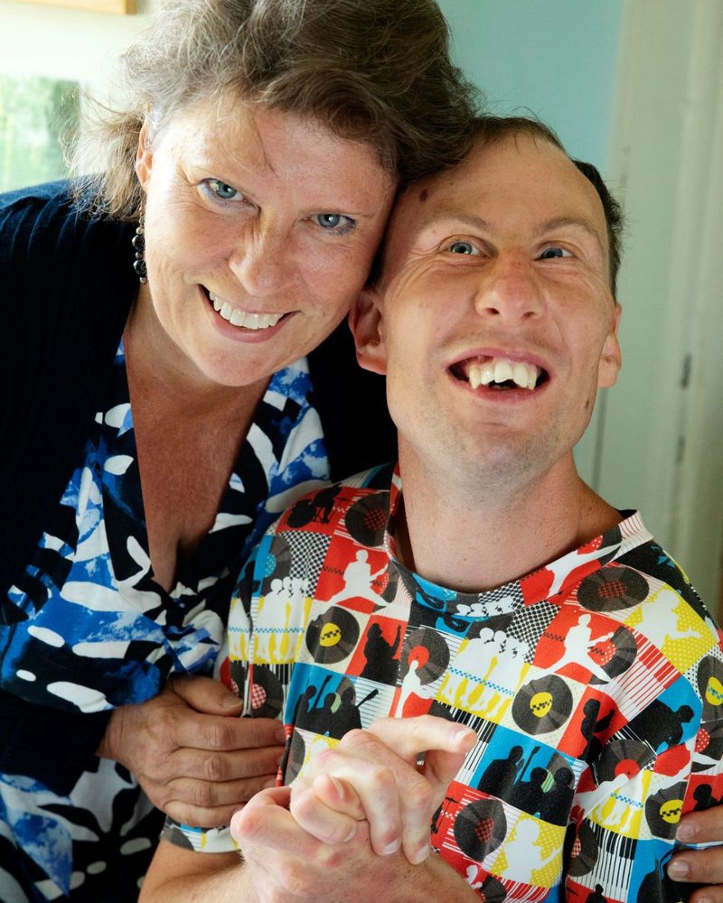 Två personer kramas och skrattar, en av dem i färgglad skjorta