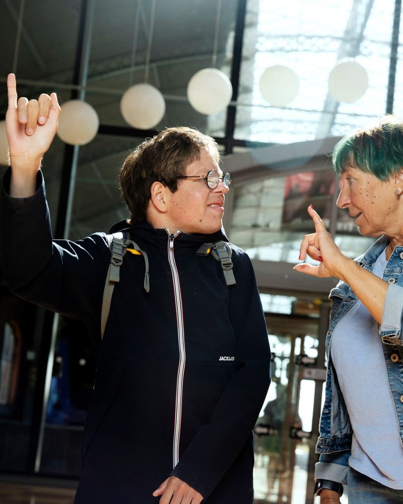 Ung man pekar uppåt i en hall med lyktor, assistenten bredvid