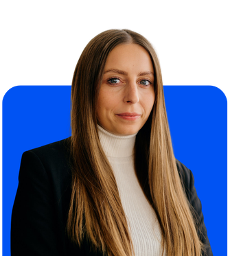 Porträt einer Frau mit langen blonden Haaren, weißem Rollkragenpullover und schwarzem Blazer vor blauem Hintergrund.