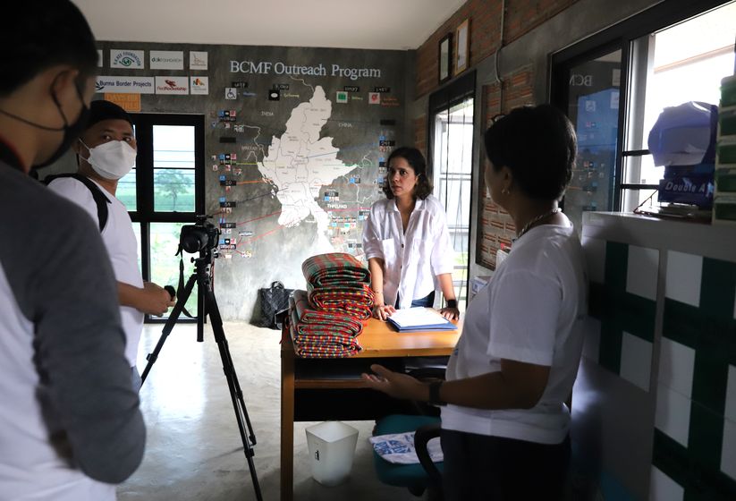 A two-person Happy Productions crew filming in a partner NGO field office