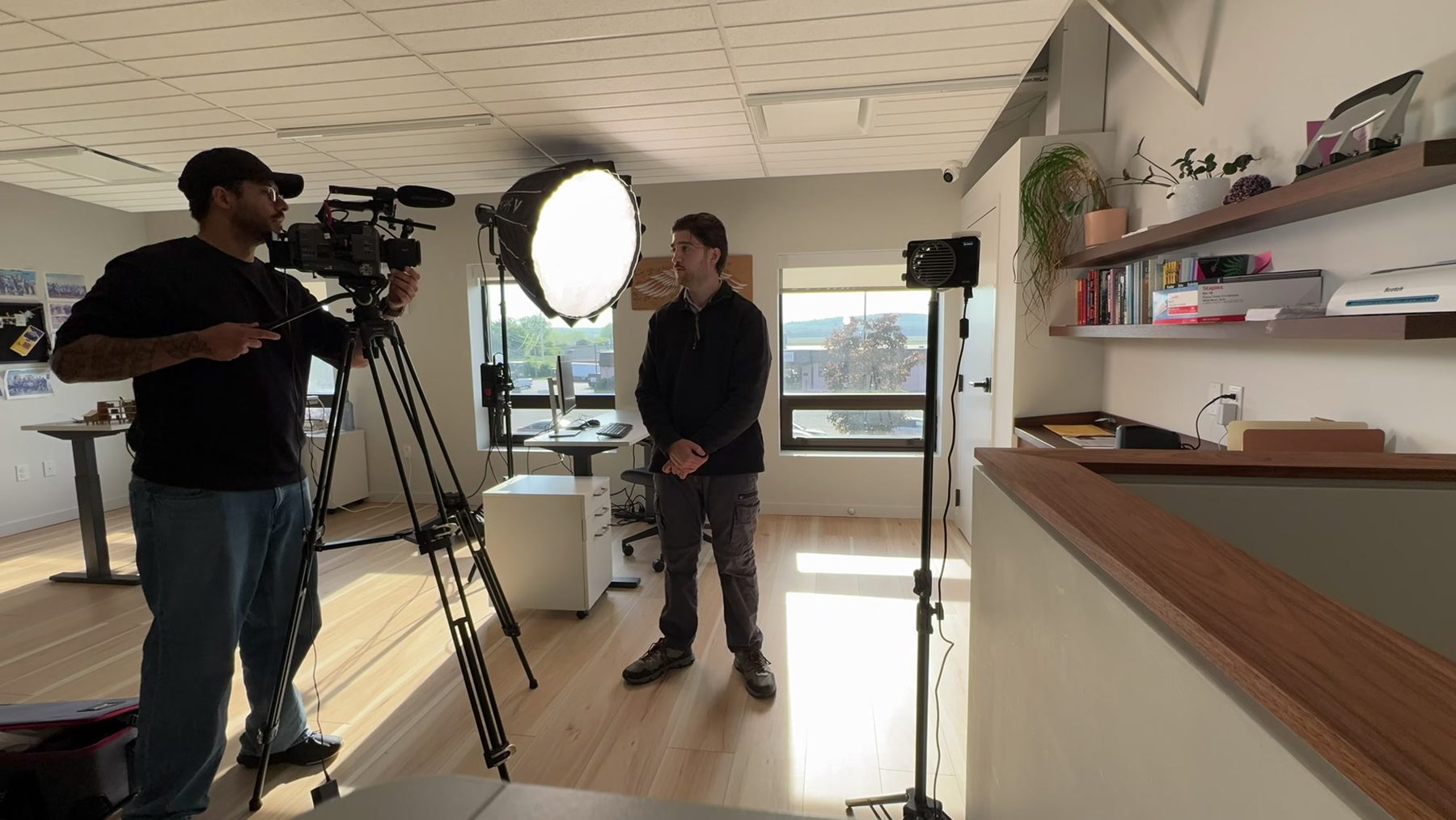 A Happy Productions crew lighting and filming an interview in an office