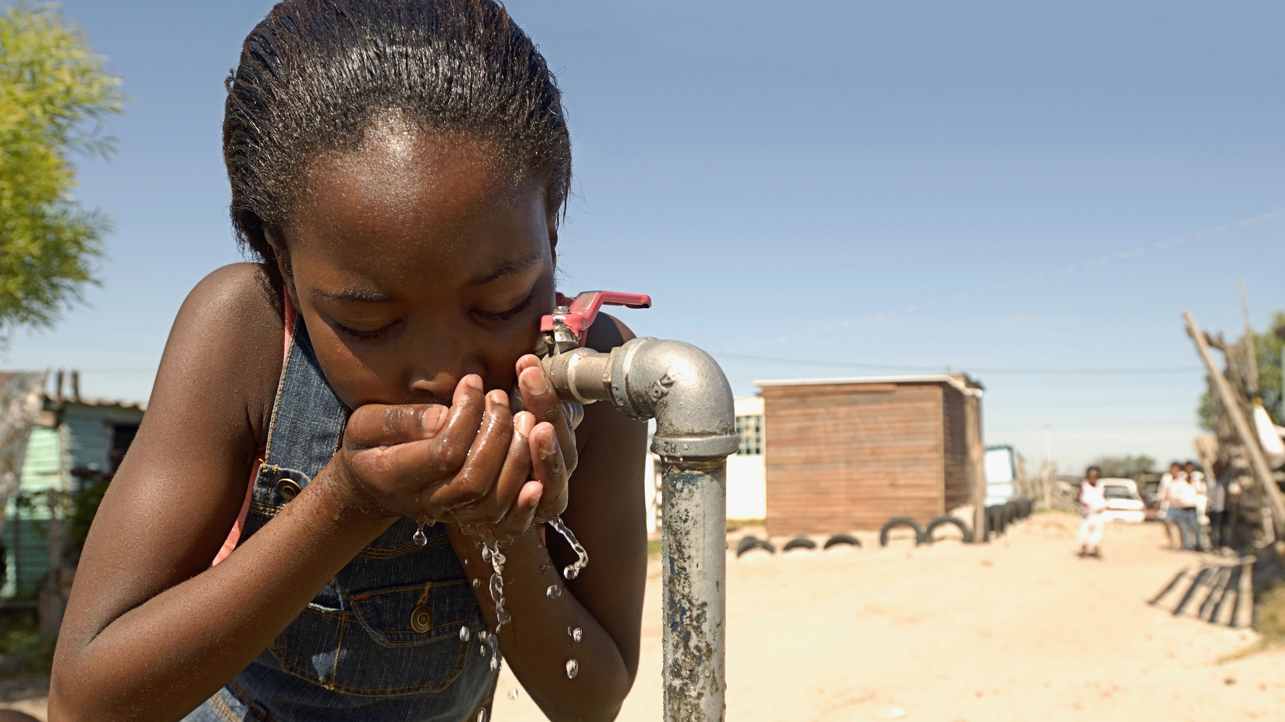Child accessing clean drinking water provided by a nonprofit initiative – Happy Productions