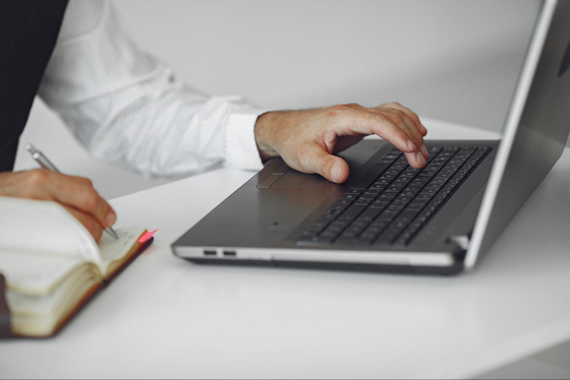 person typing on laptop and taking notes on what is programmatic seo