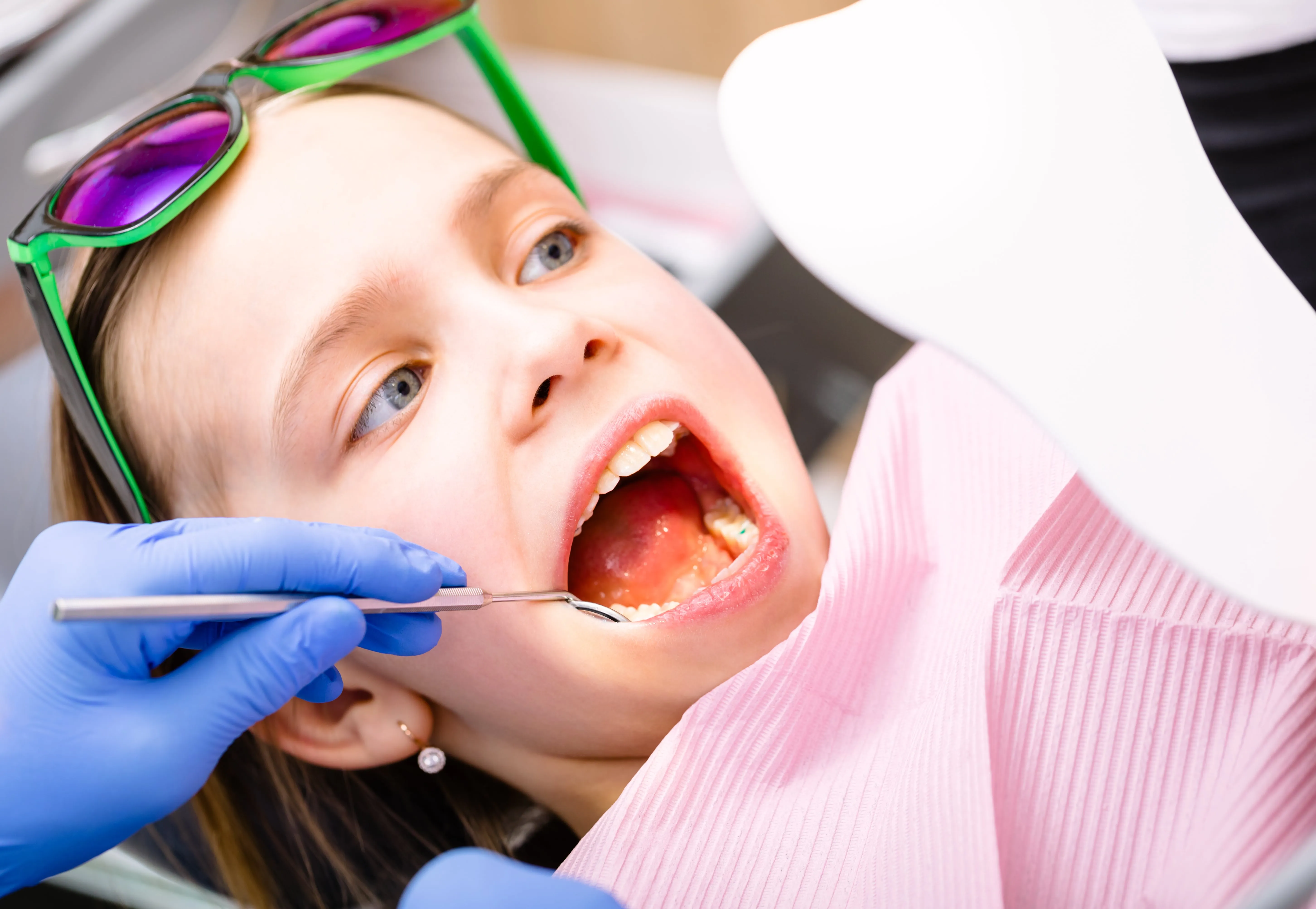 A young girl getting her teeth checked by a dentist.