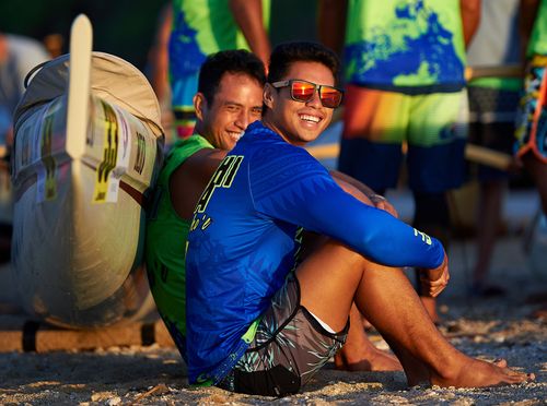 Canoe paddlers sitting on the beach before the 2019 Molokaʻi Hoe