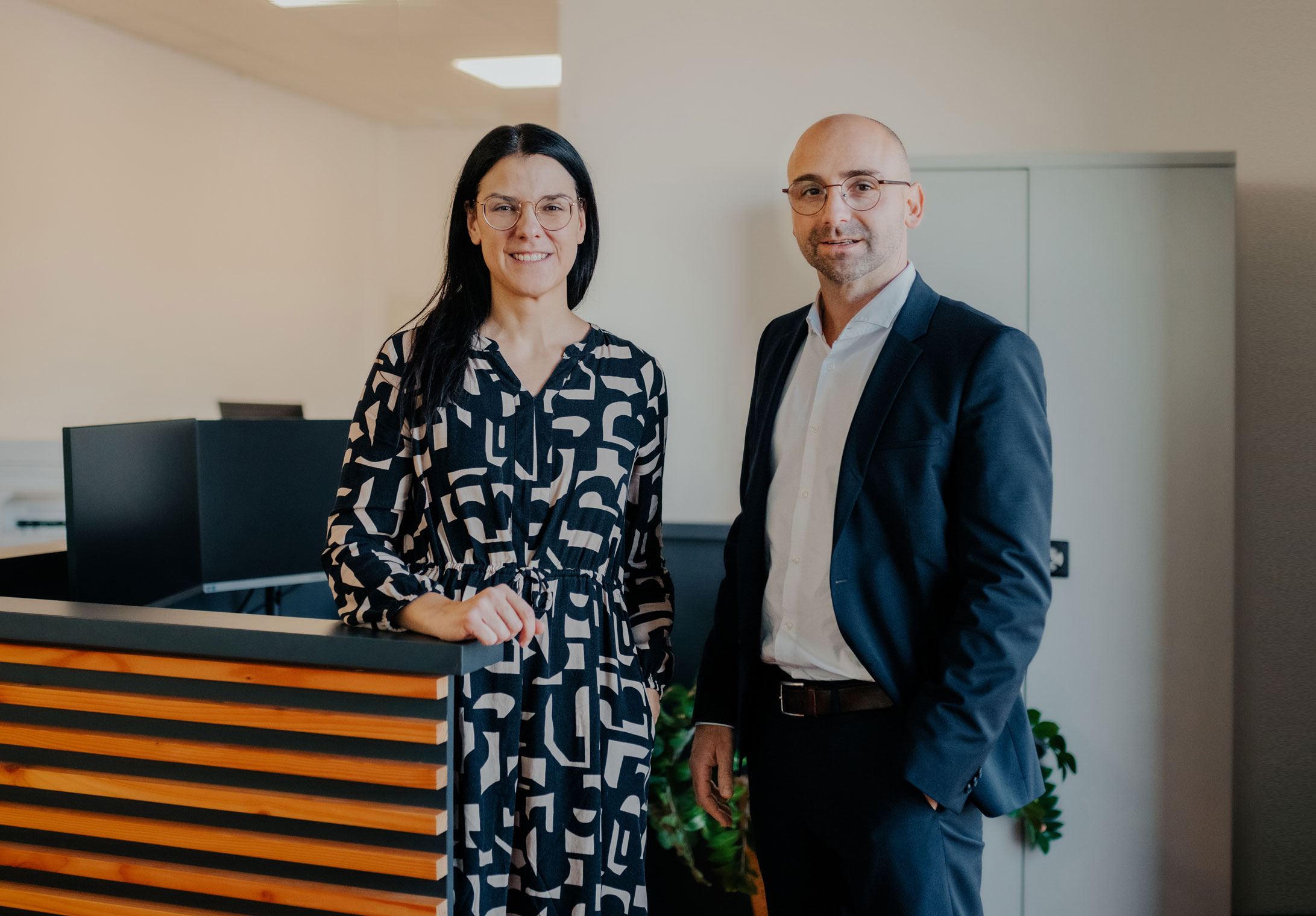 Die Geschäftsführer stehen lächelnd an Empfang