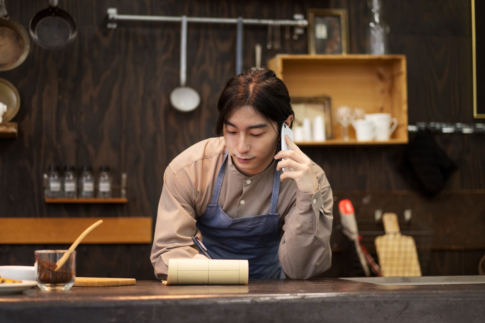 chef in the kitchen making a phone call and taking notes